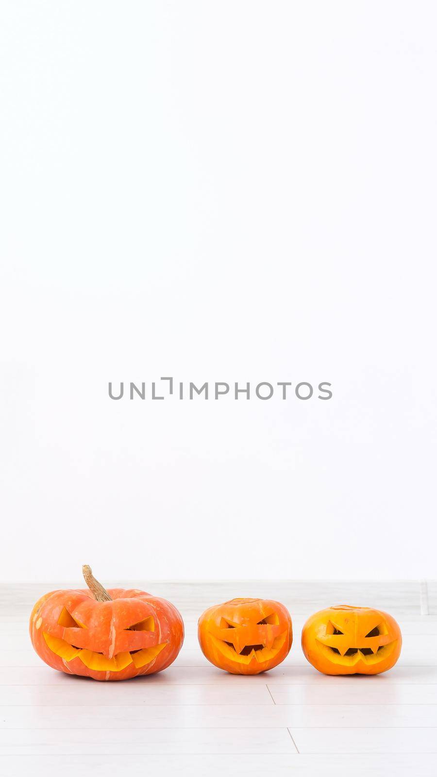 Jack-o-lantern carved pumpkin on light wall background with copy space, autumn and halloween home decor.