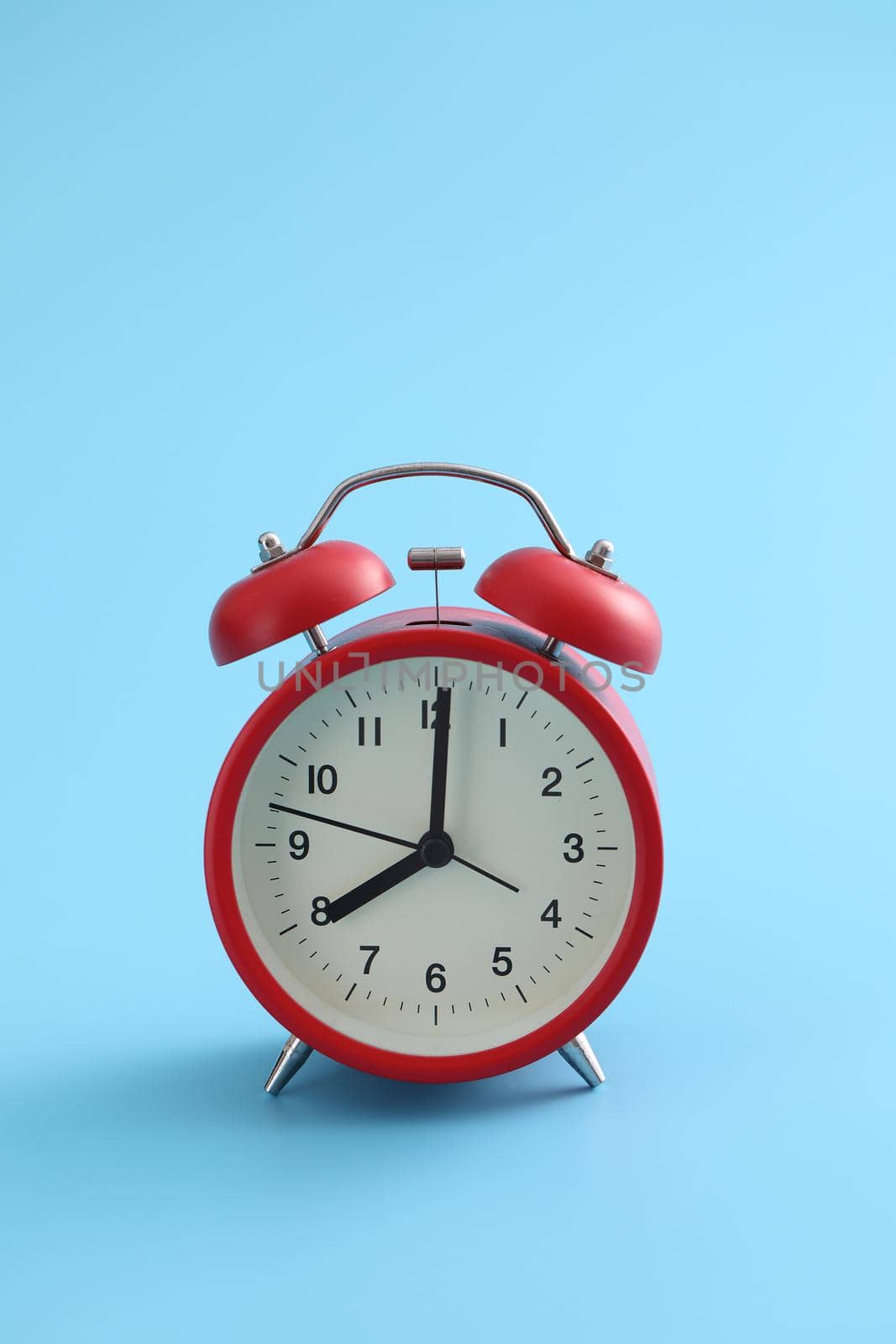 Red retro alarm clock isolated on a blue background
