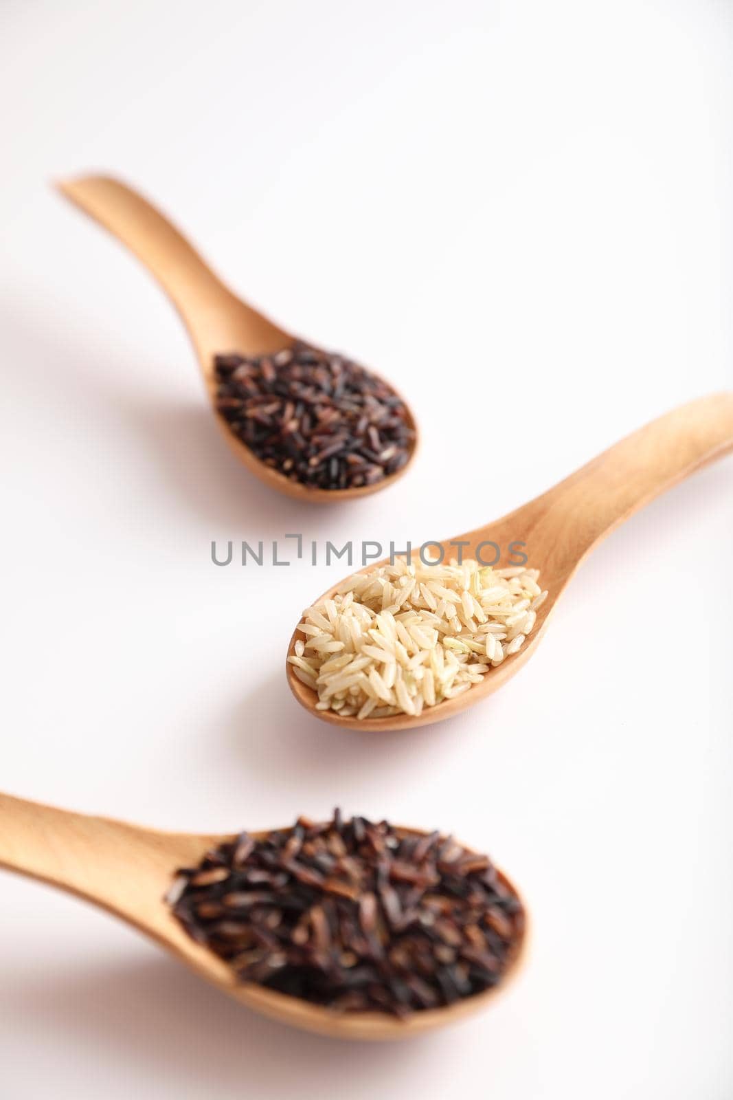 Organic raw brown rice and riceberry rice on spoon in close up by piyato