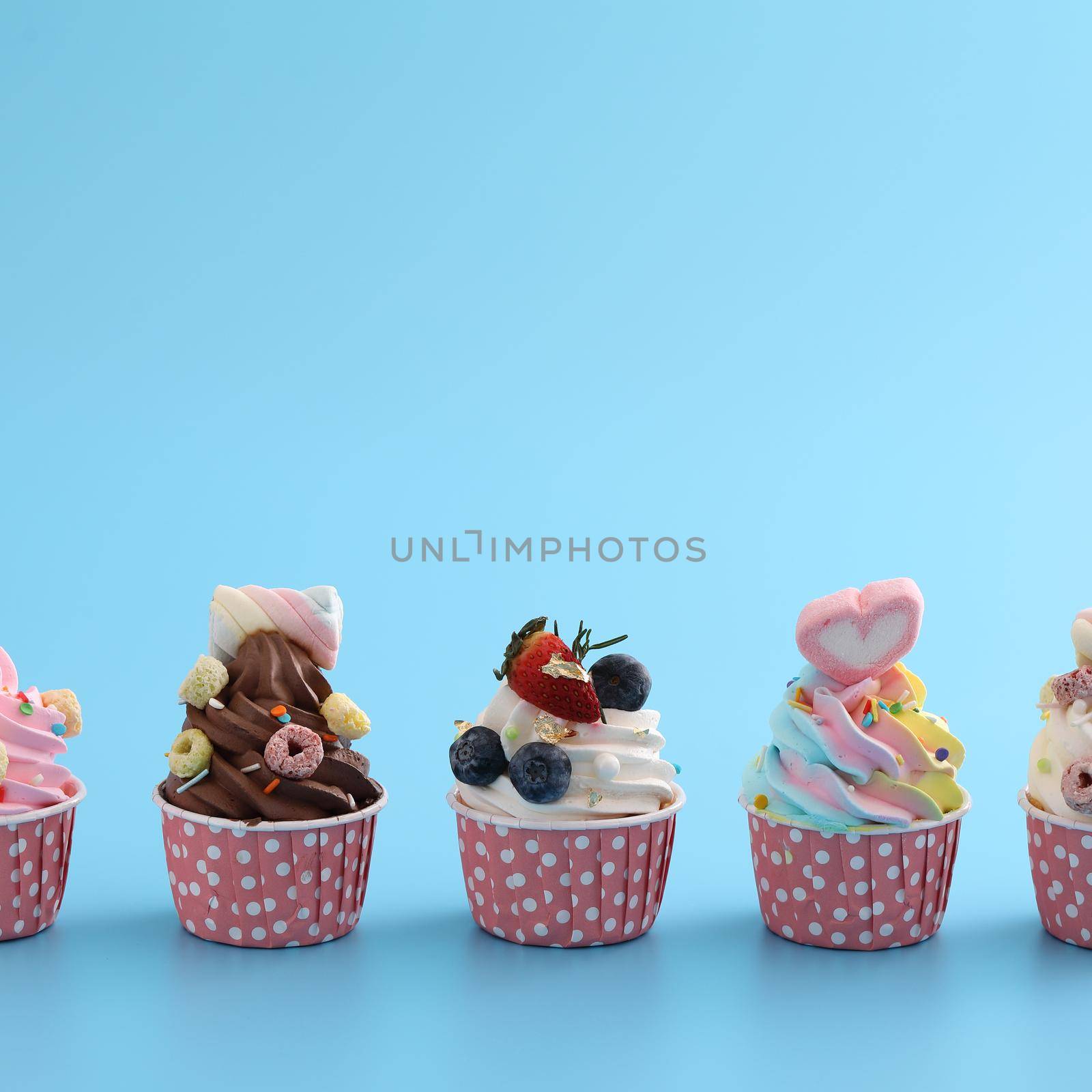 Colorful cupcakes isolated in blue background