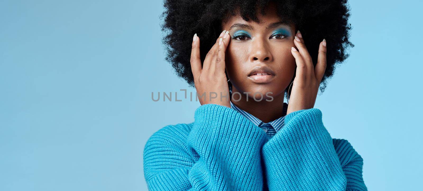 Blue makeup, fashion and beauty with a black woman in studio against a wall background with mockup. Cosmetics, face and eye shadow with a young female posing for contemporary or edgy style by YuriArcurs