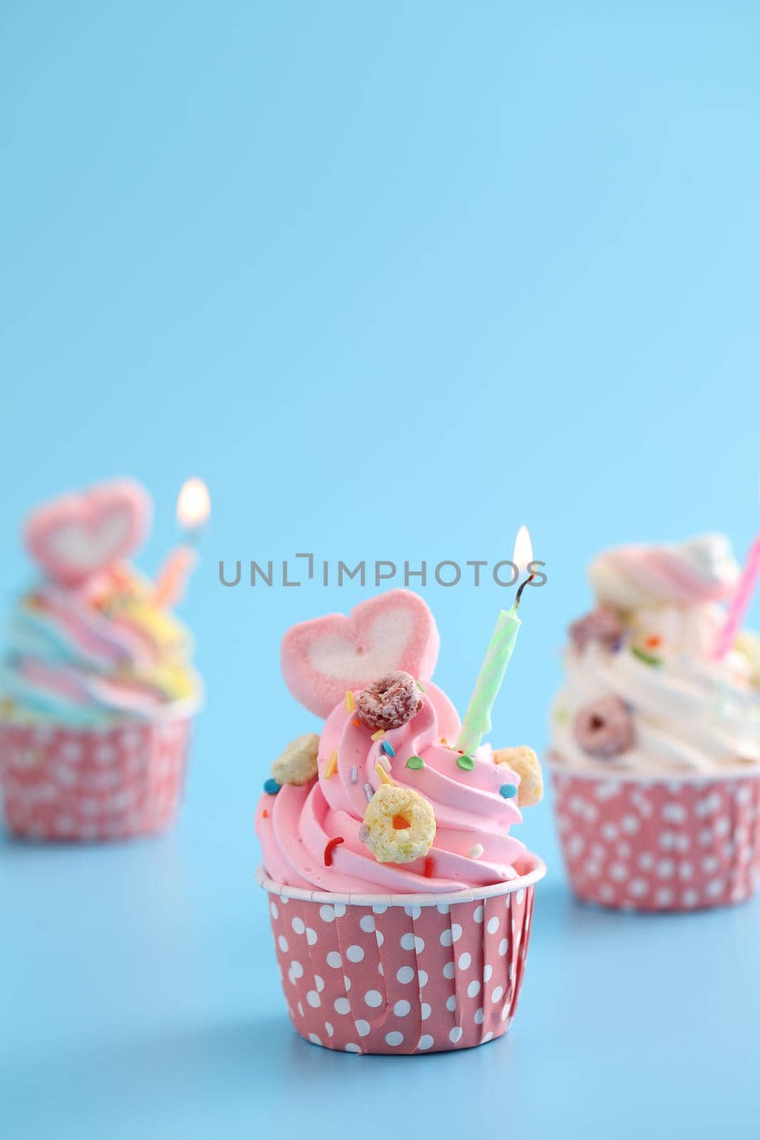 Colorful cupcakes with candle isolated in blue background by piyato