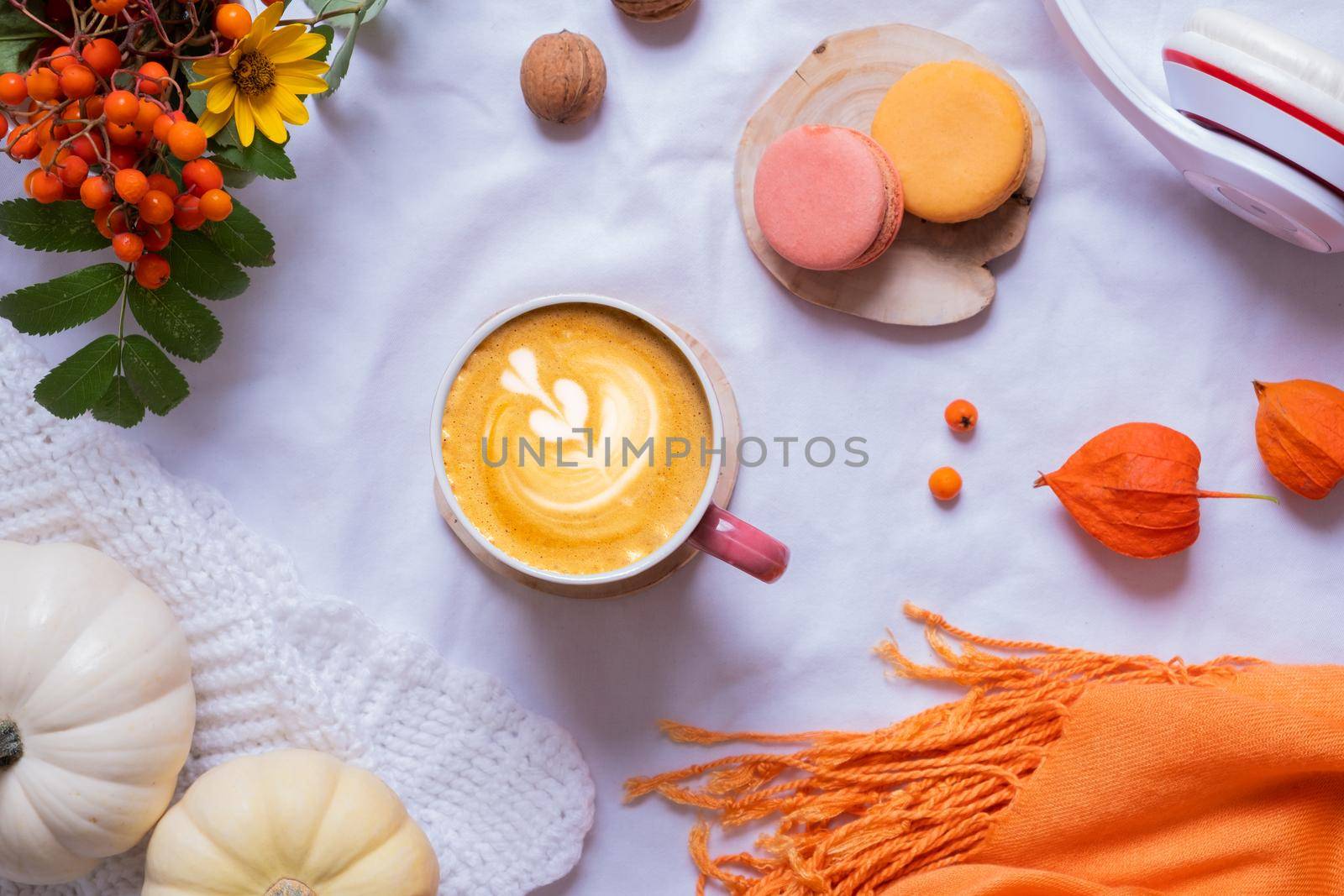 Cup of latte and autumn cozy decor with sweater and pumpkins top view.