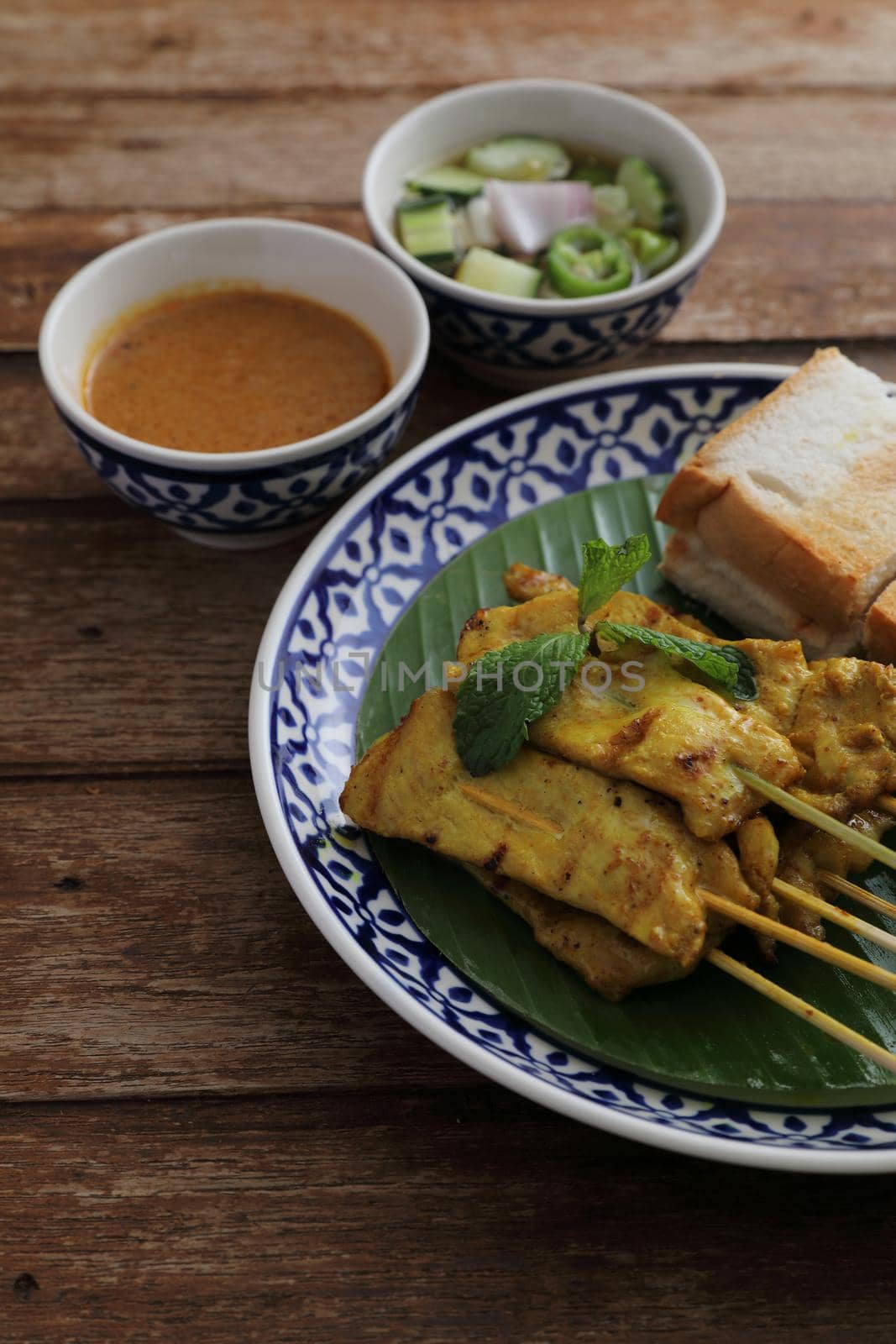 Local Thai food pork satay with oeanut dipping sauce isolated in wood background by piyato