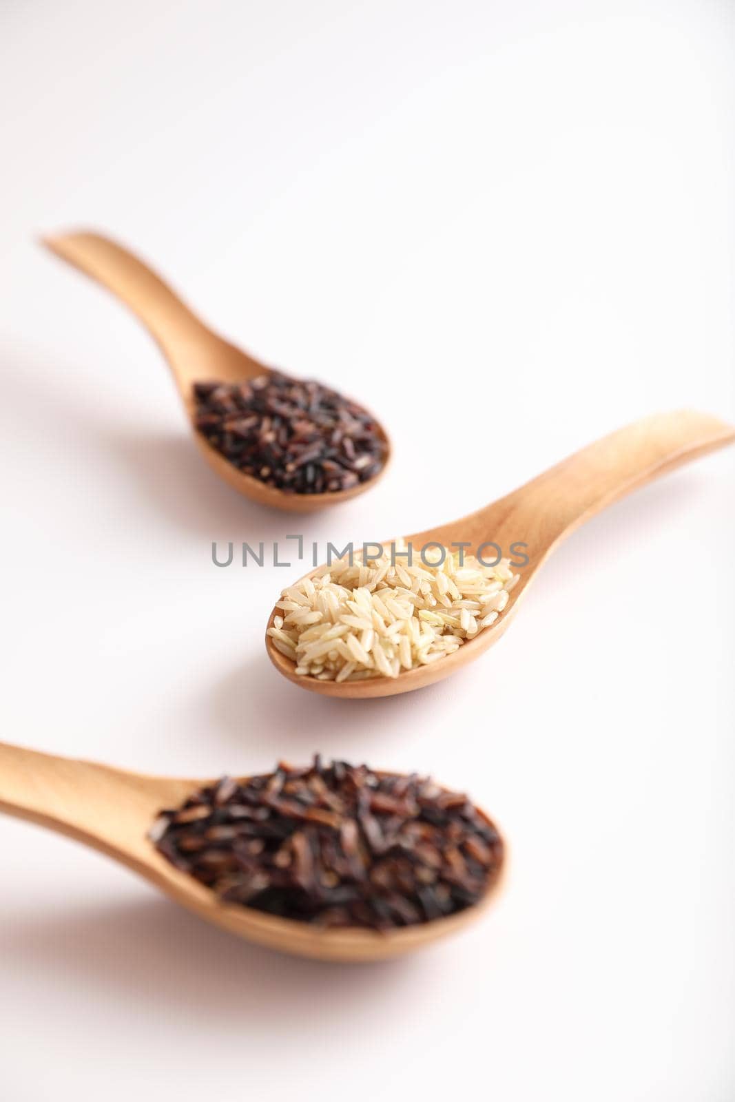 Organic raw brown rice and riceberry rice on spoon in close up