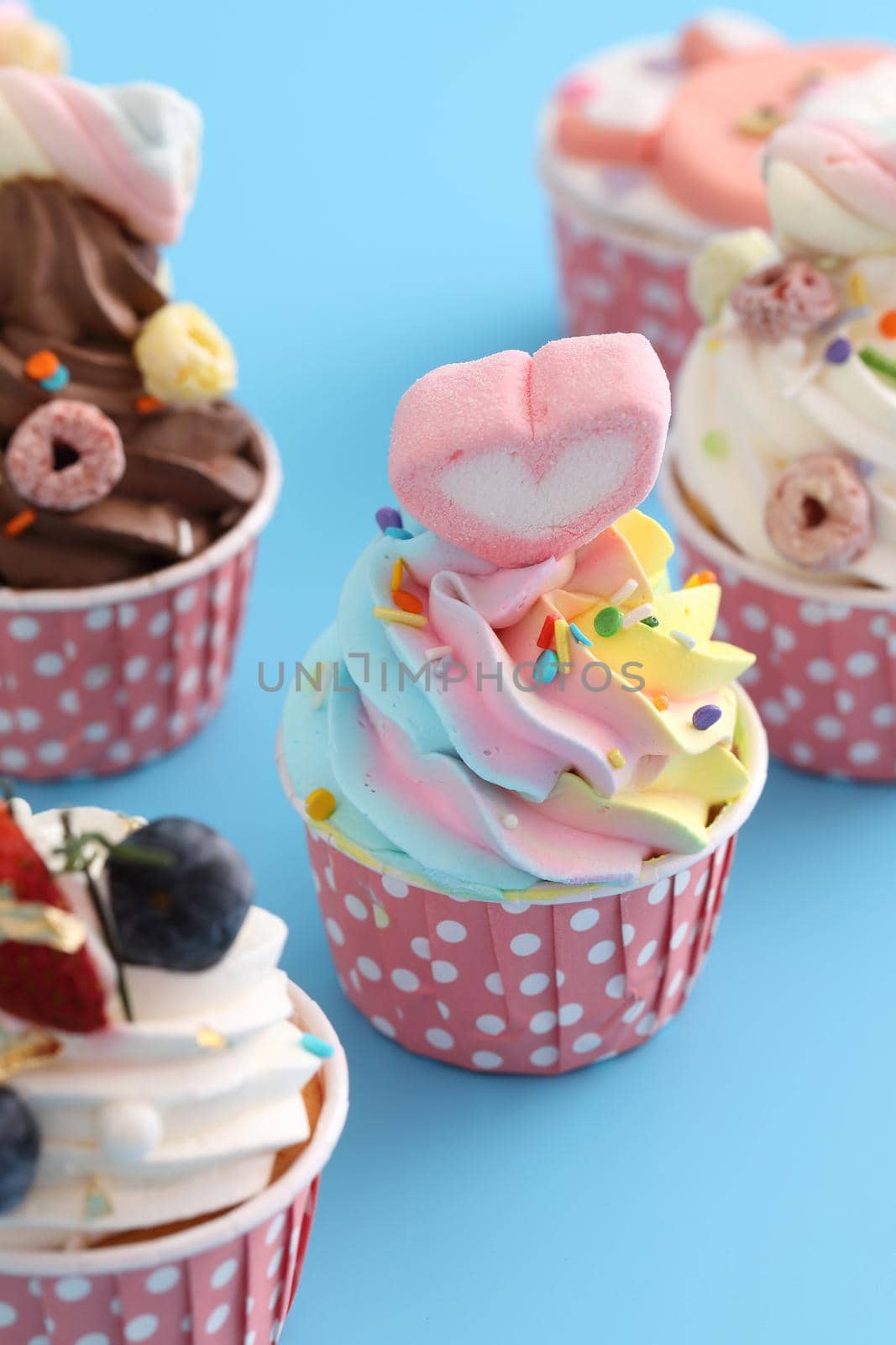Colorful cupcakes isolated in blue background by piyato