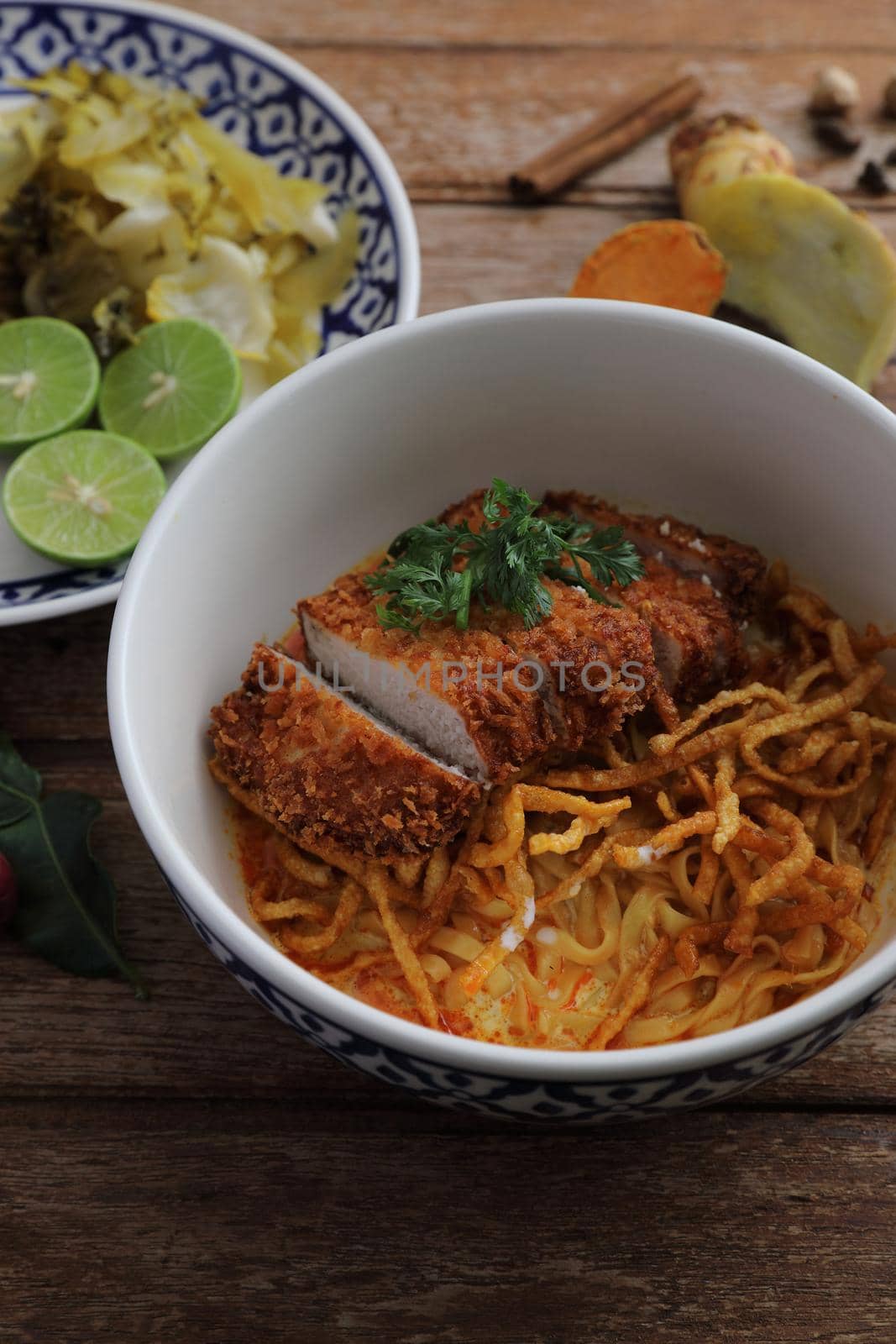 Local northern Thai food Egg noodle curry with fried pork on wood background by piyato