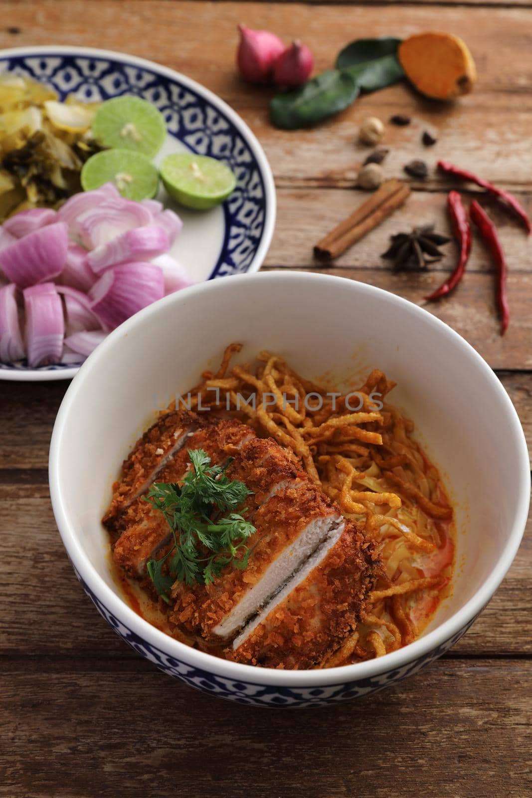 Local northern Thai food Egg noodle curry with fried pork on wood background by piyato