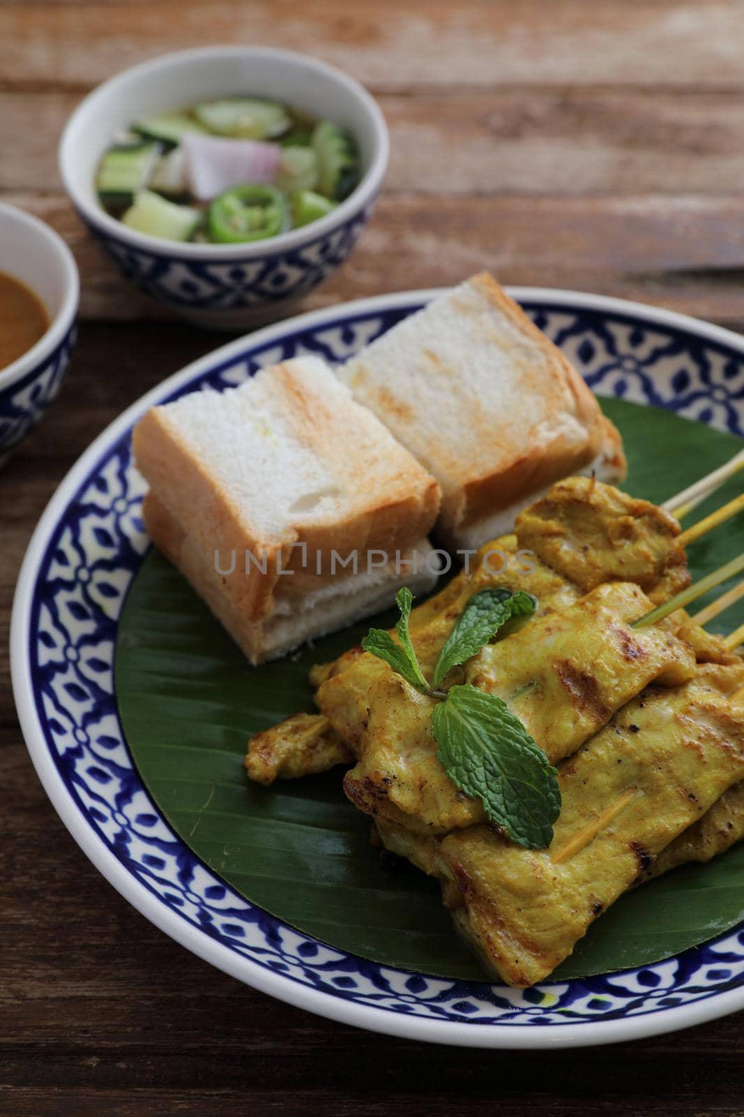 Local Thai food pork satay with oeanut dipping sauce isolated in wood background by piyato