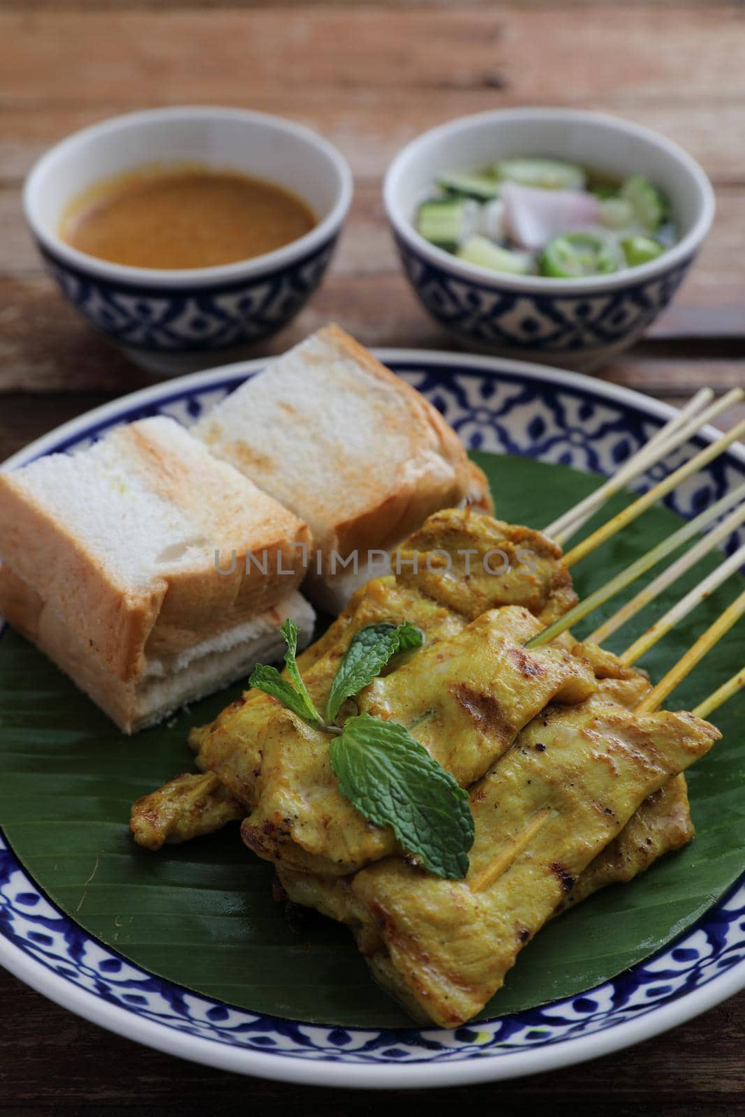 Local Thai food pork satay with oeanut dipping sauce isolated in wood background