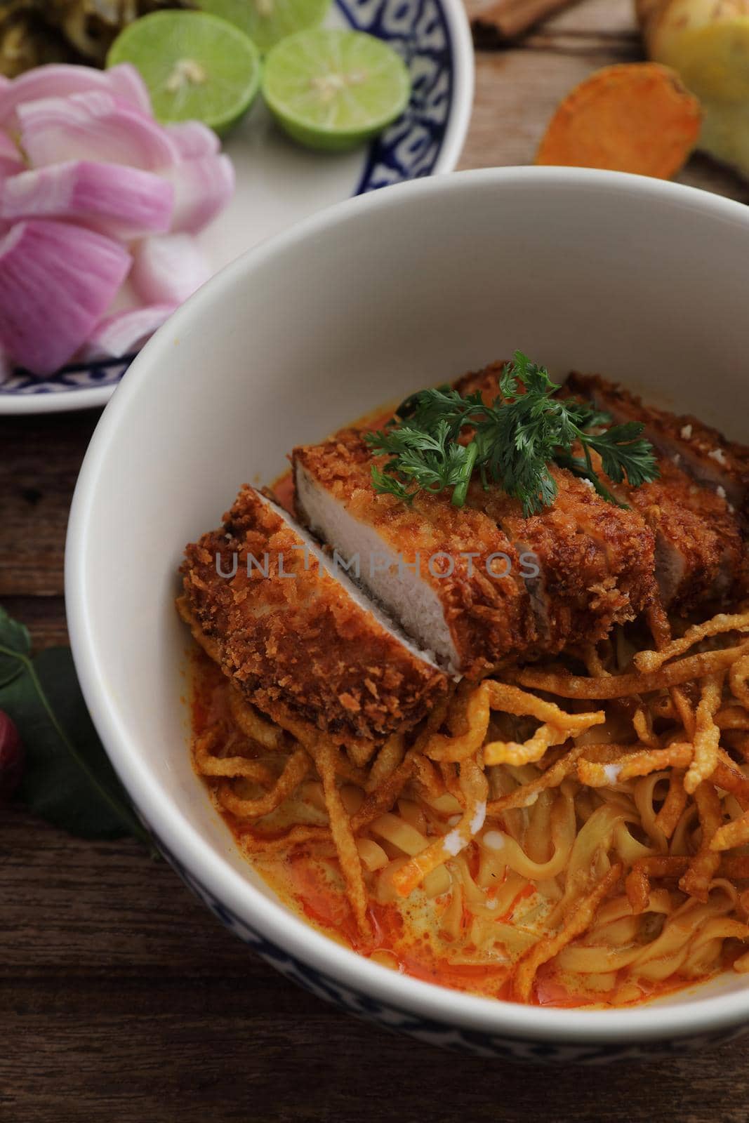 Local northern Thai food Egg noodle curry with fried pork on wood background by piyato