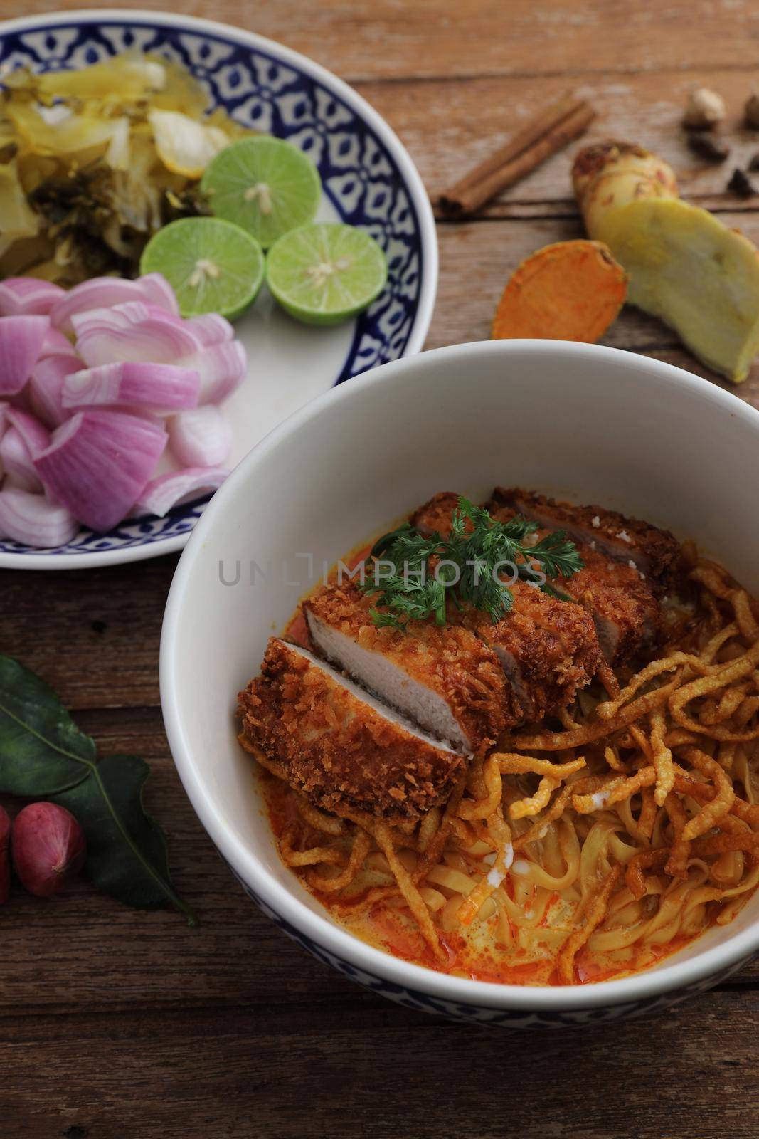 Local northern Thai food Egg noodle curry with fried pork on wood background