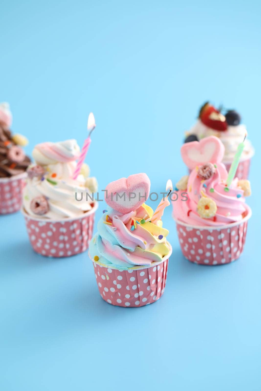 Colorful cupcakes with candle isolated in blue background