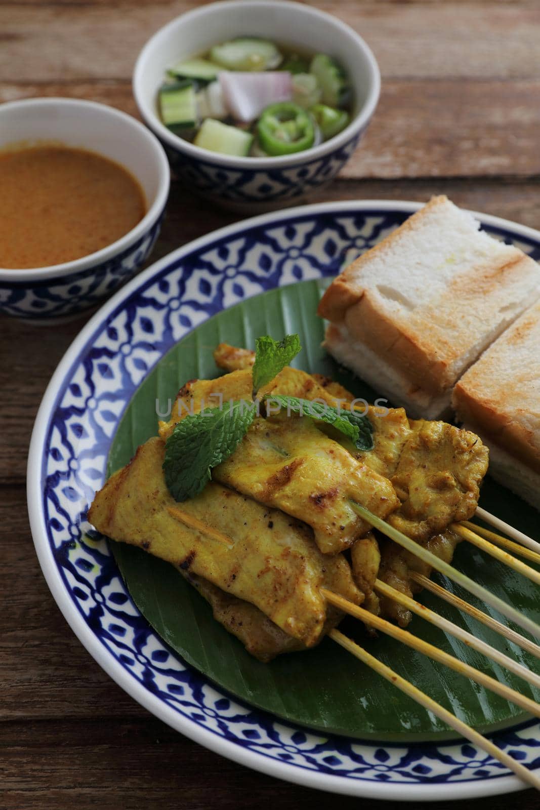 Local Thai food pork satay with oeanut dipping sauce isolated in wood background by piyato