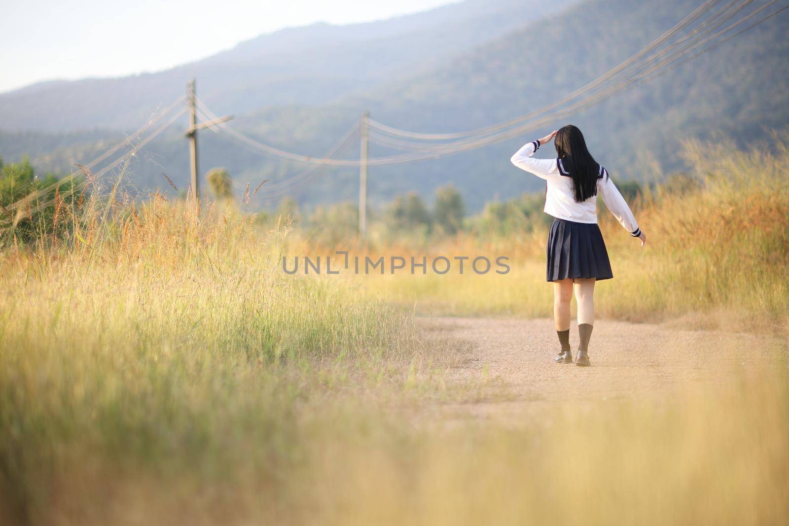 Asian High School Girls student walking in countryside with sunrise by piyato