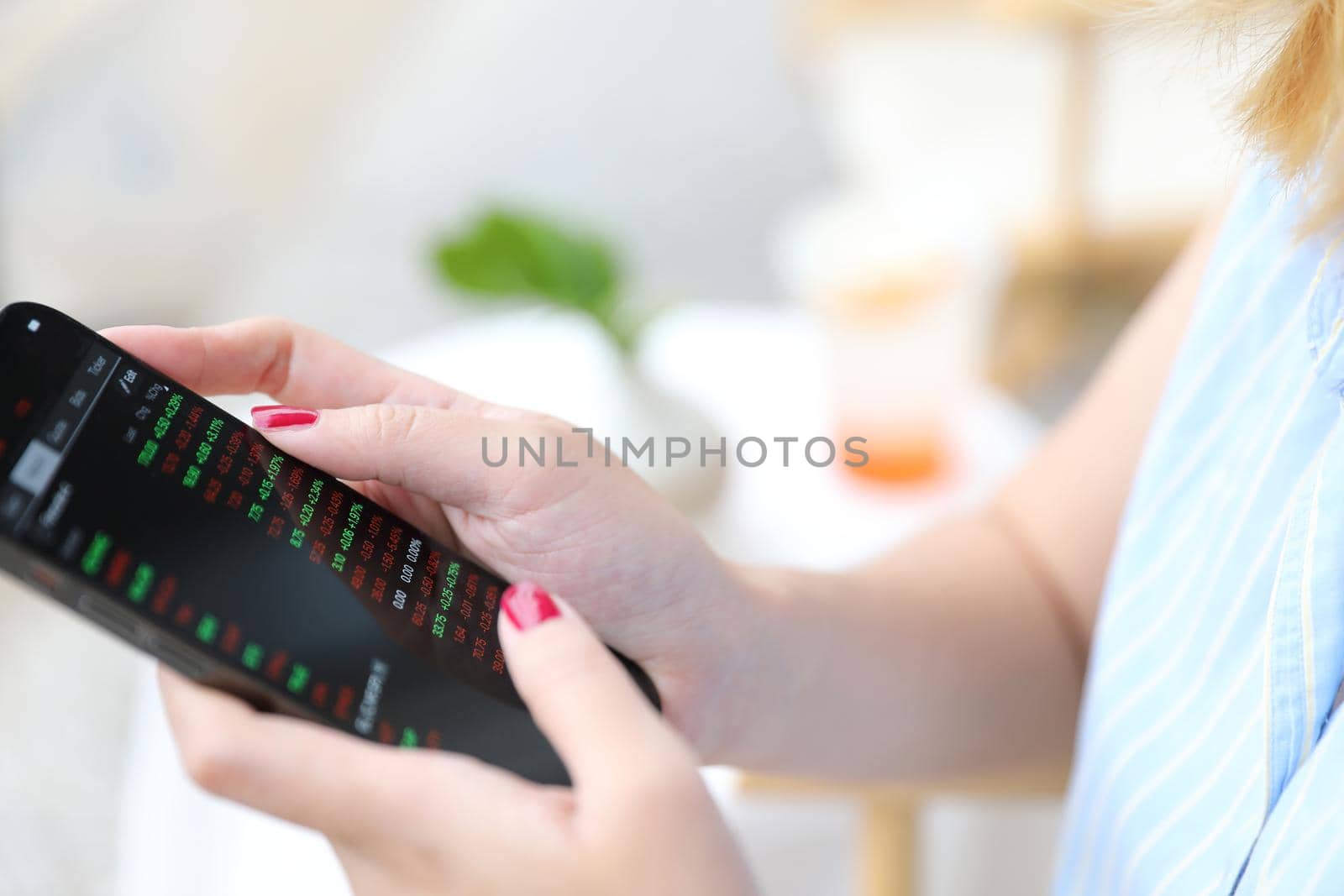 Female hand with smartphone trading stocks online in coffee shop Business concept