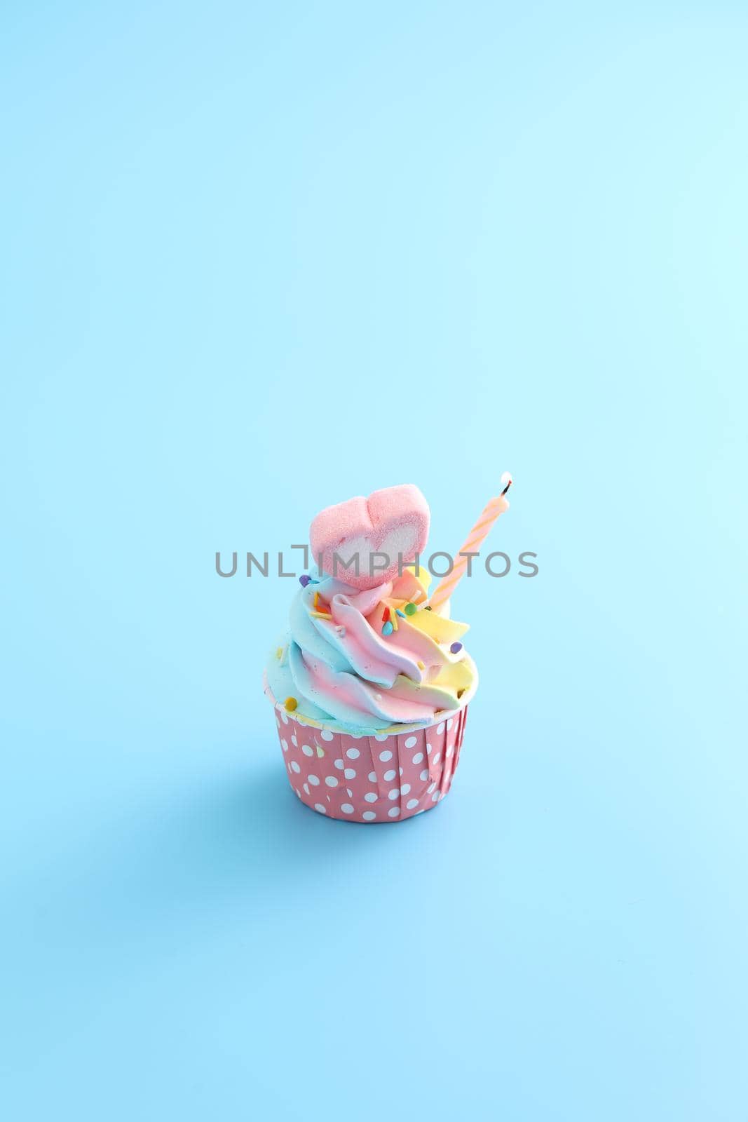 Colorful cupcake with candle isolated in blue background