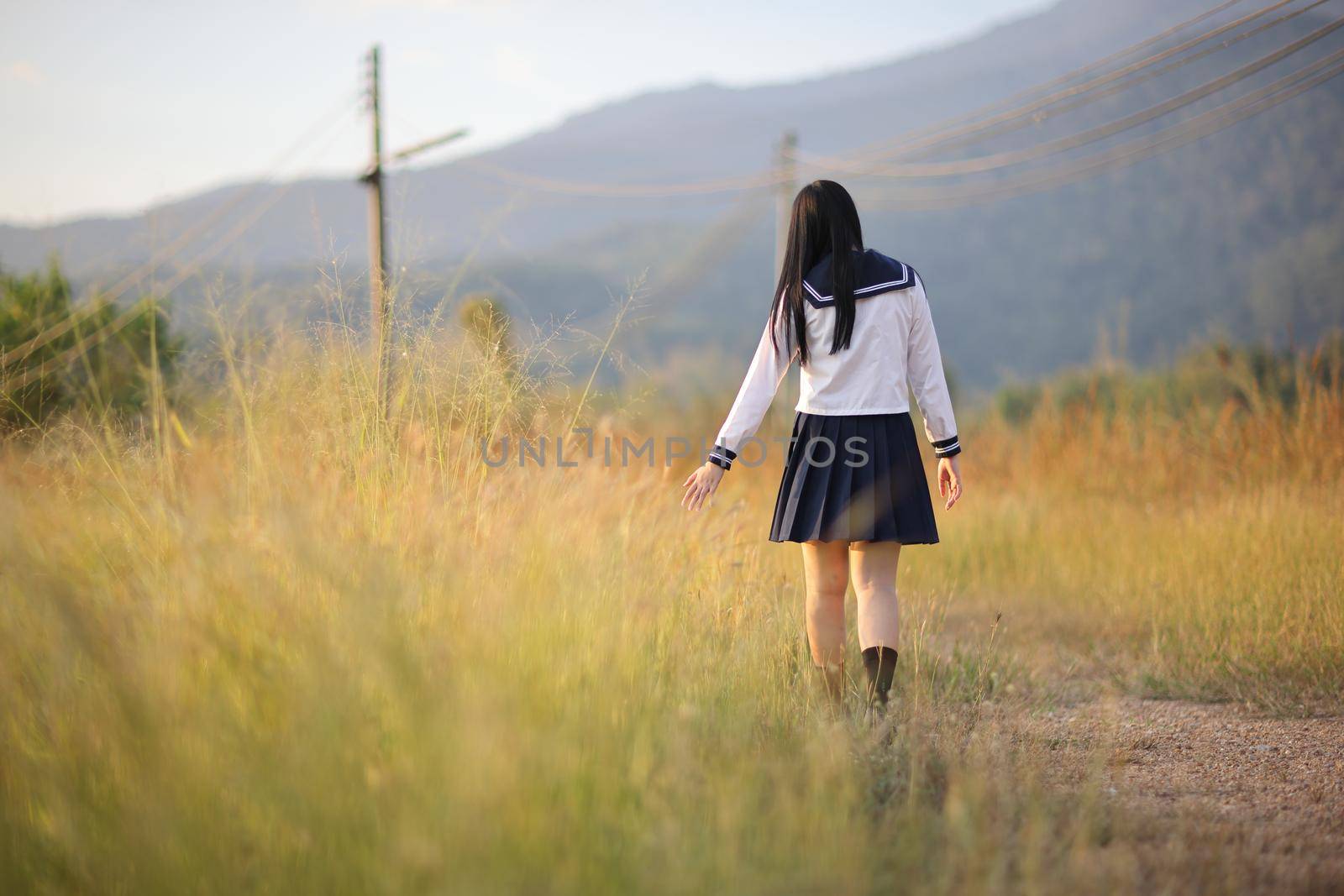 Asian High School Girls student walking in countryside with sunrise