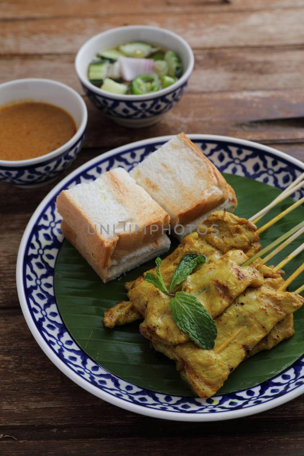 Local Thai food pork satay with oeanut dipping sauce isolated in wood background by piyato