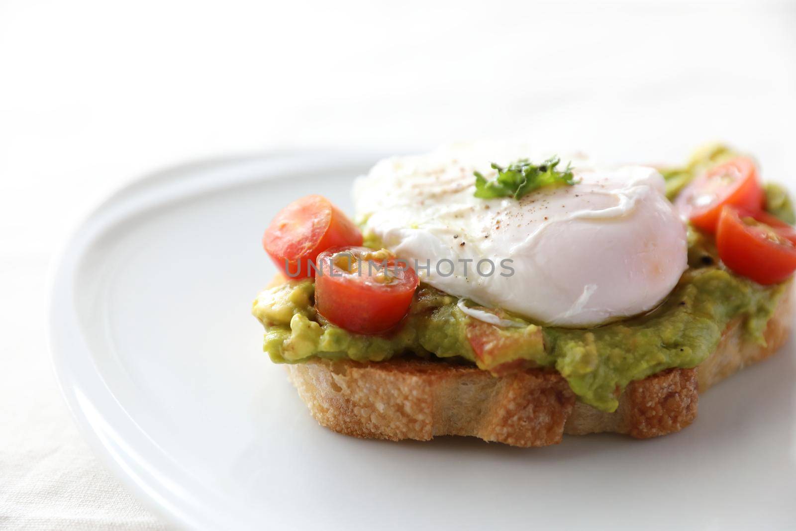 Poached eggs with avocado on toast in white background