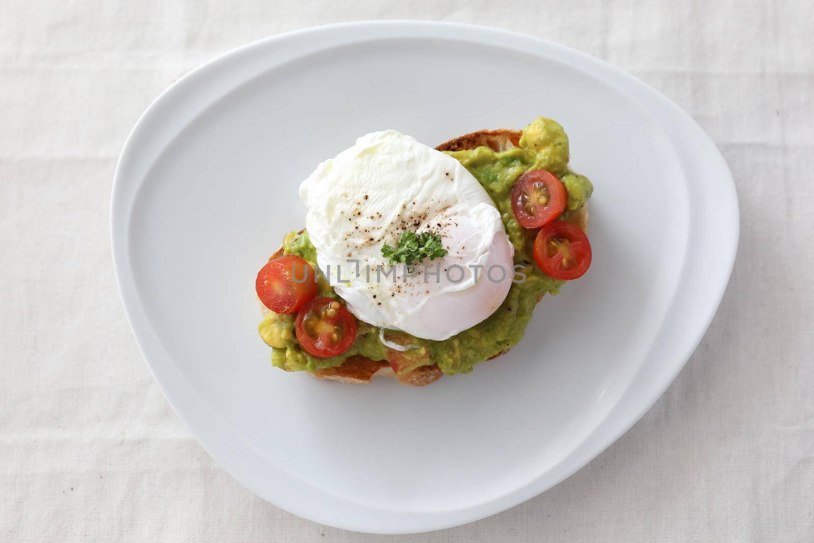 Poached eggs with avocado on toast in white background by piyato