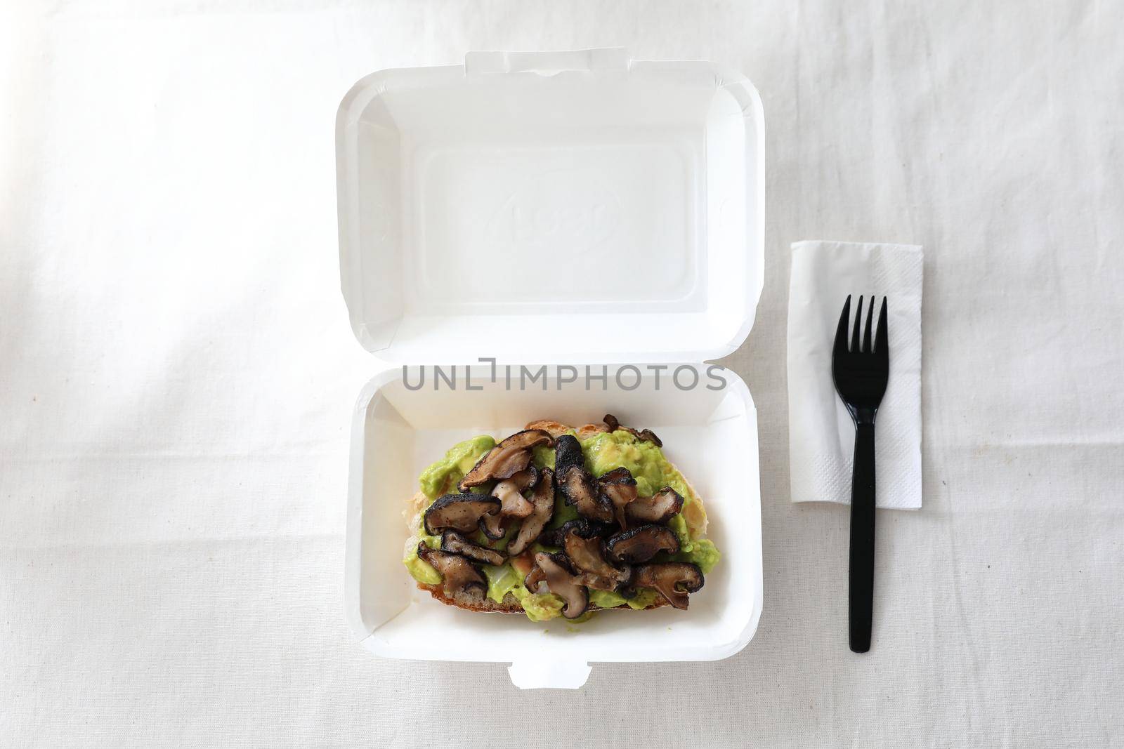 Toast with avocado and grilled mushroom with delivery package in white background