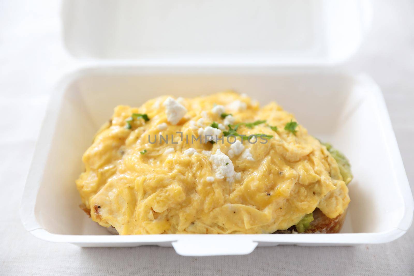 Avocado and scrambled eggs toast with delivery package in white background by piyato