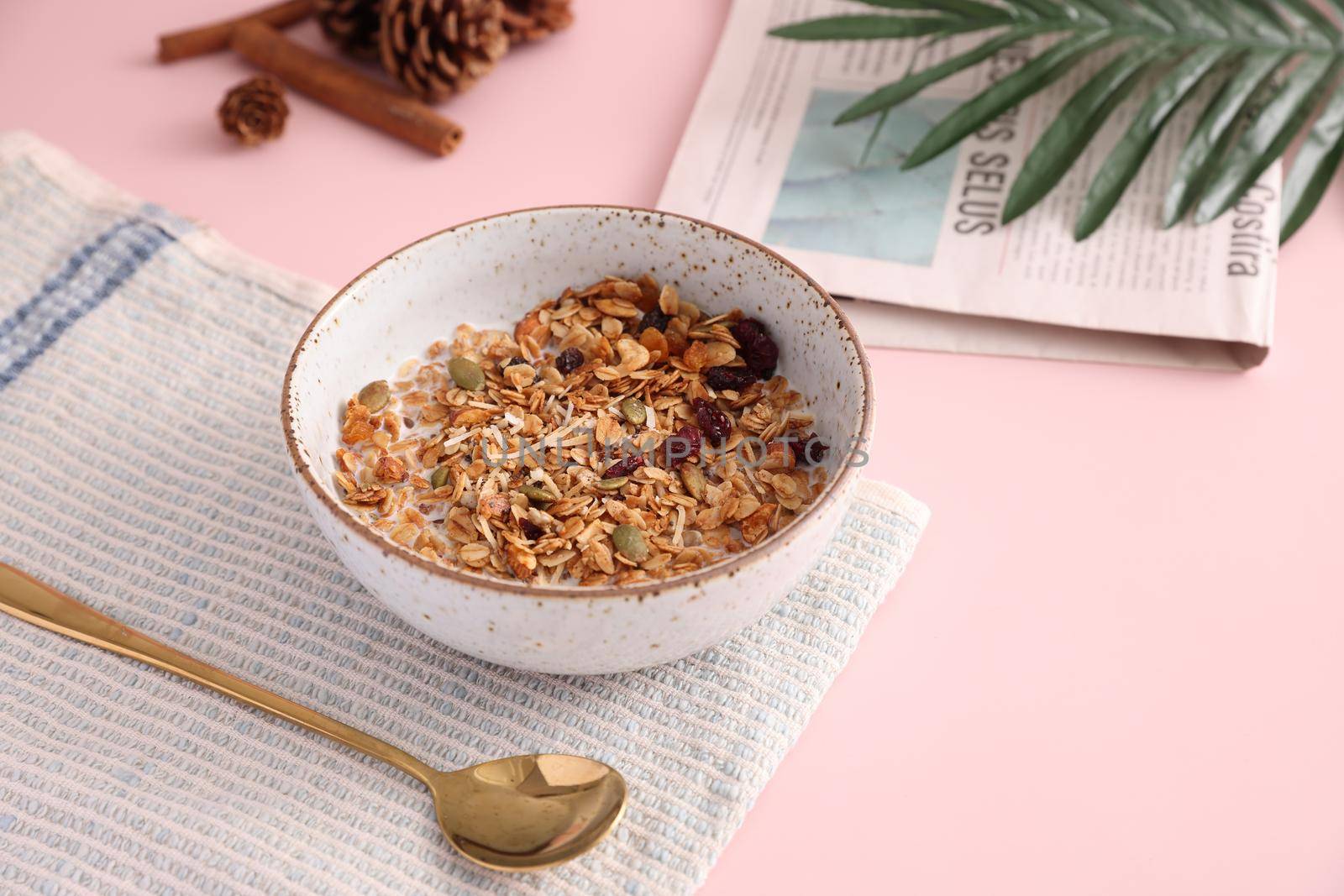 granola with milk with spoon isolated in pink background