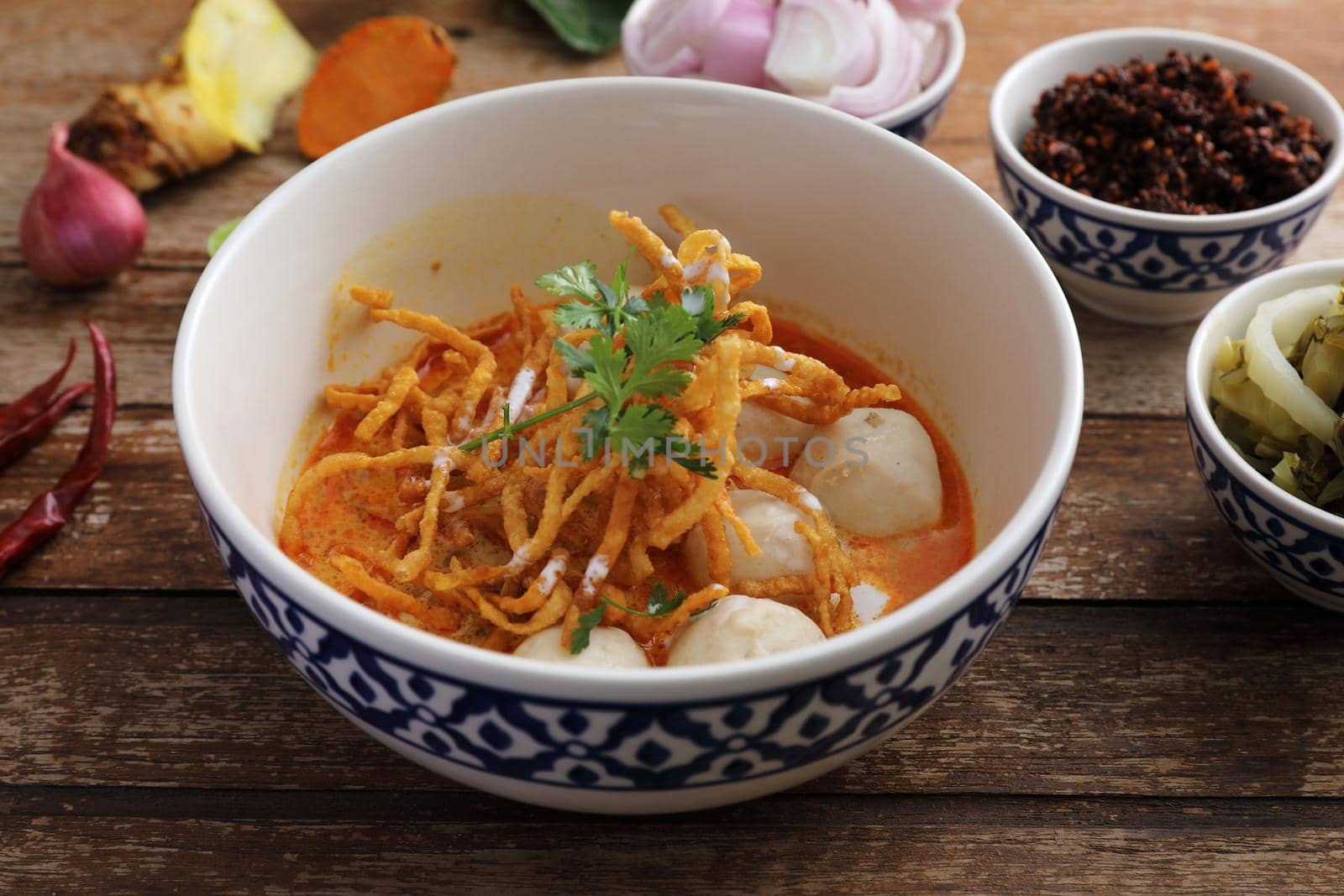 Local northern Thai food Egg noodle curry with meatballs on wood background by piyato