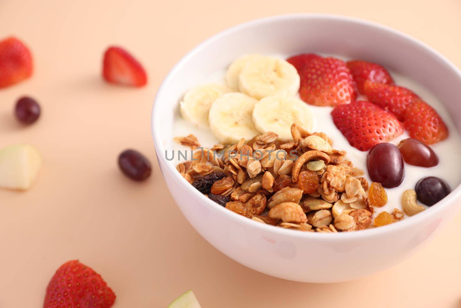 bowl of granola cereal with yogurt and berries isolated on eggnog color background by piyato