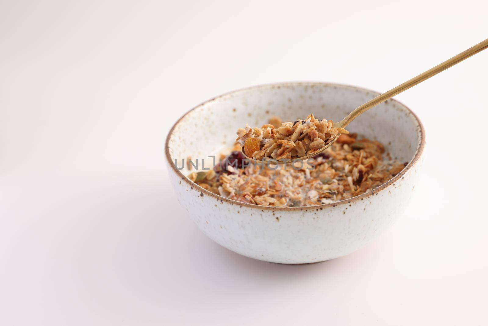 granola with milk with spoon isolated in white background