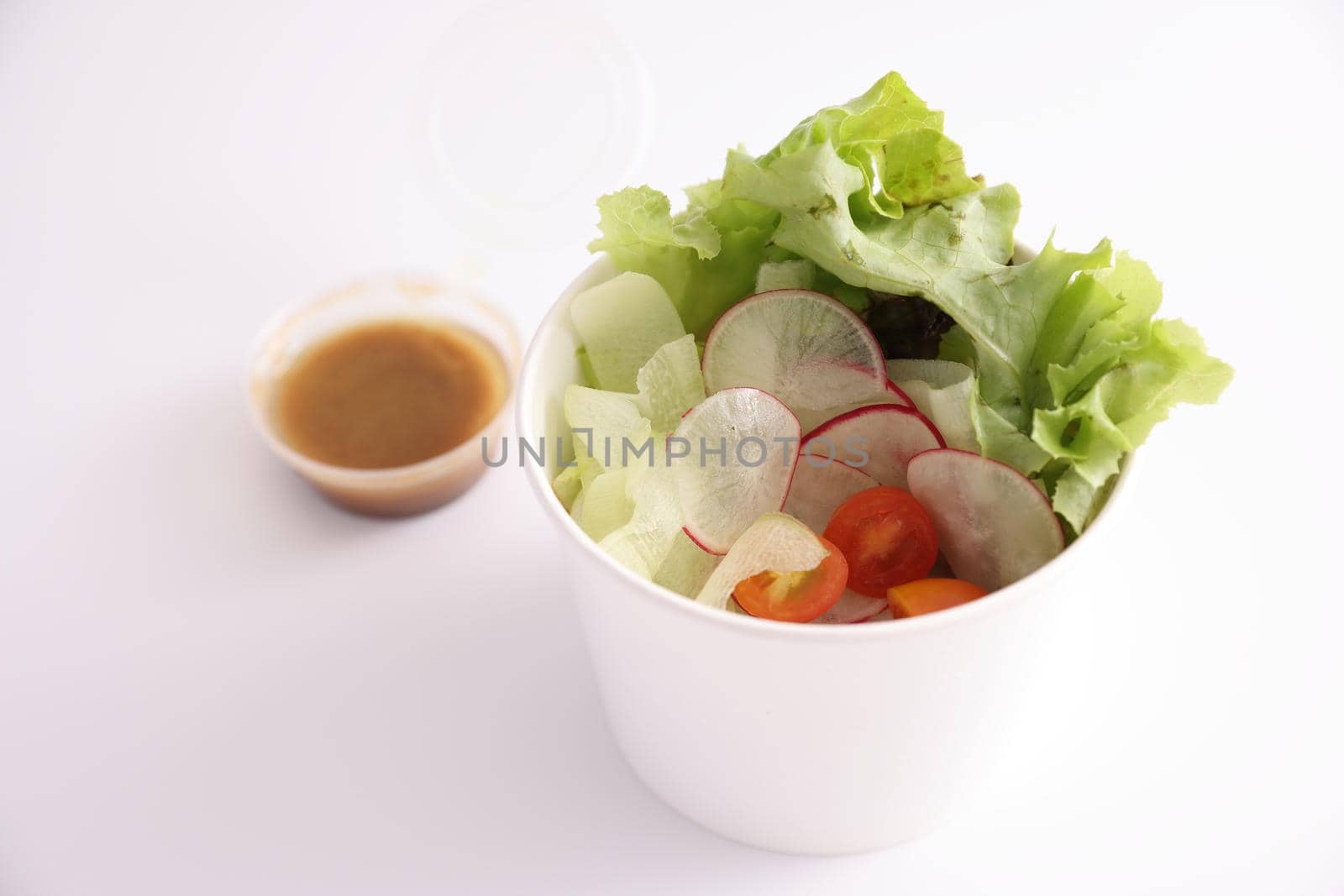 Salad in plastic package for take away or food delivery isolated on white background by piyato