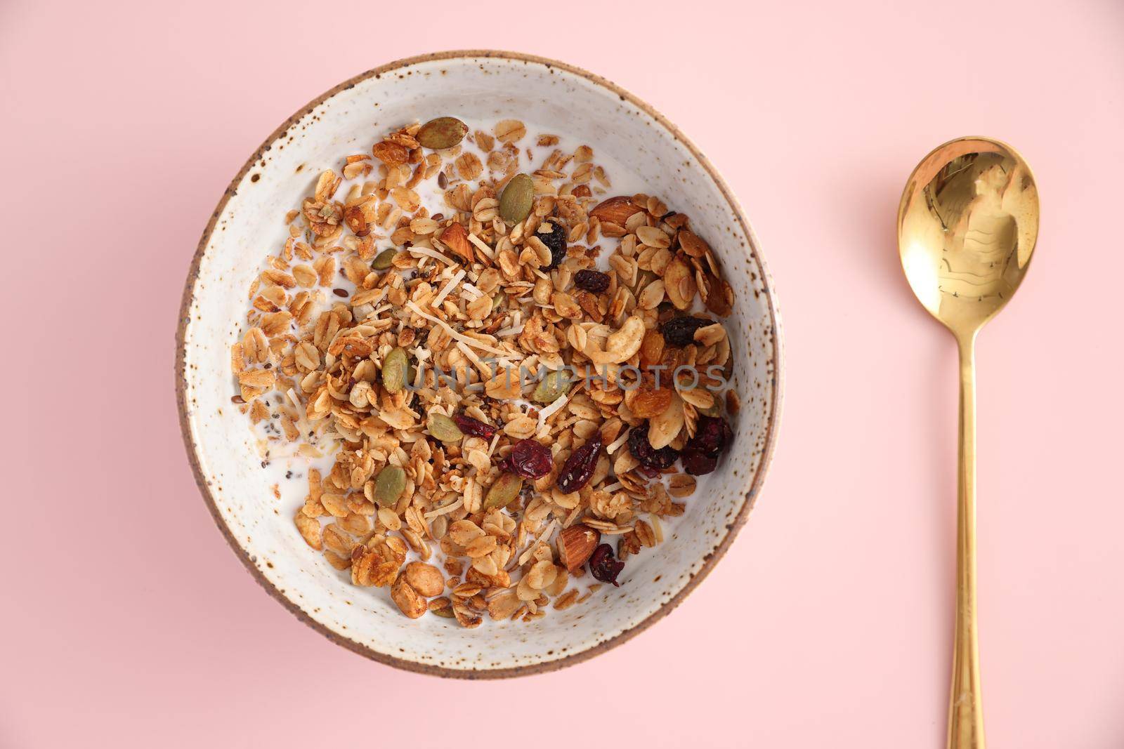 granola with milk with spoon isolated in pink background by piyato
