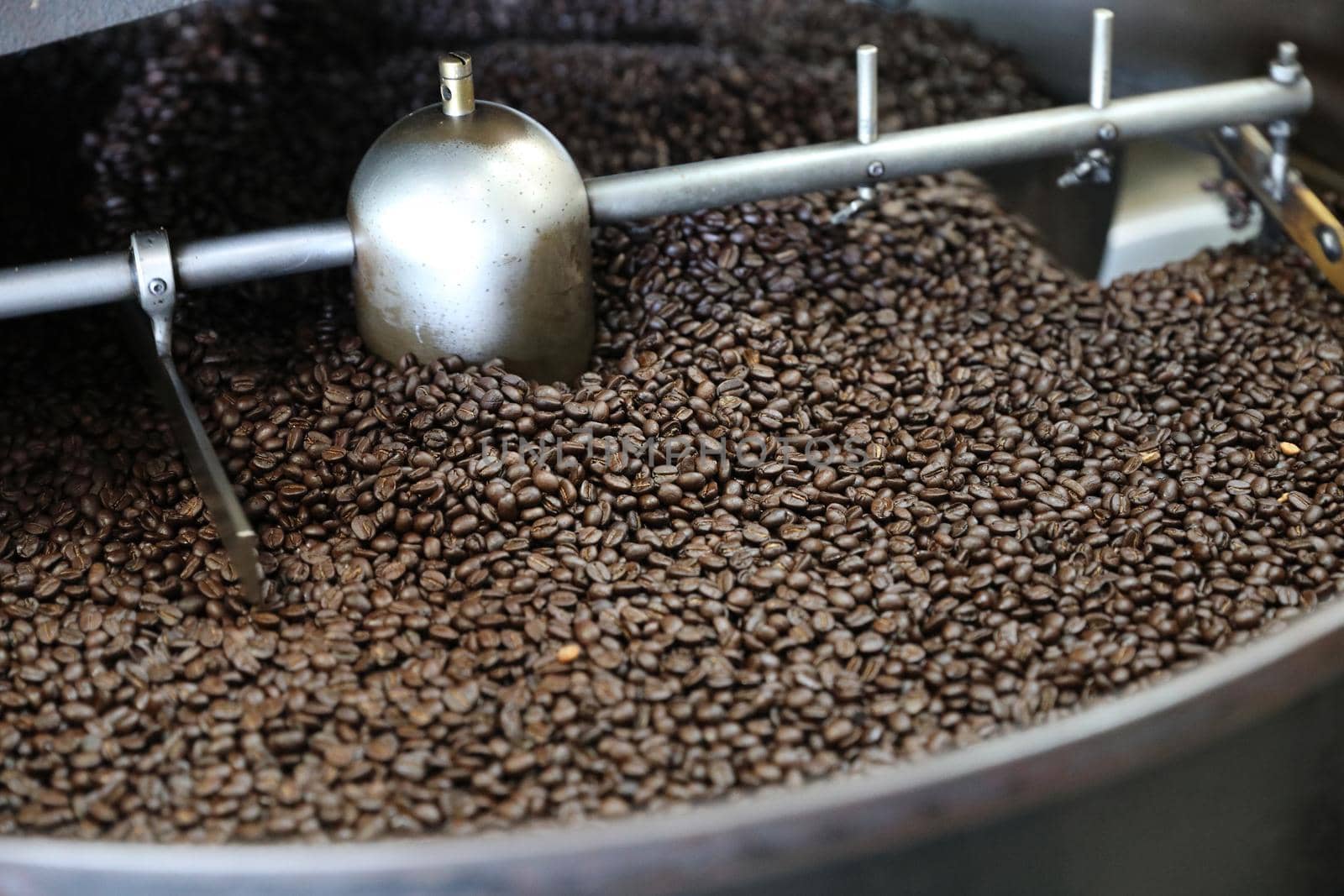 Coffee beans roasting with machine in close up by piyato