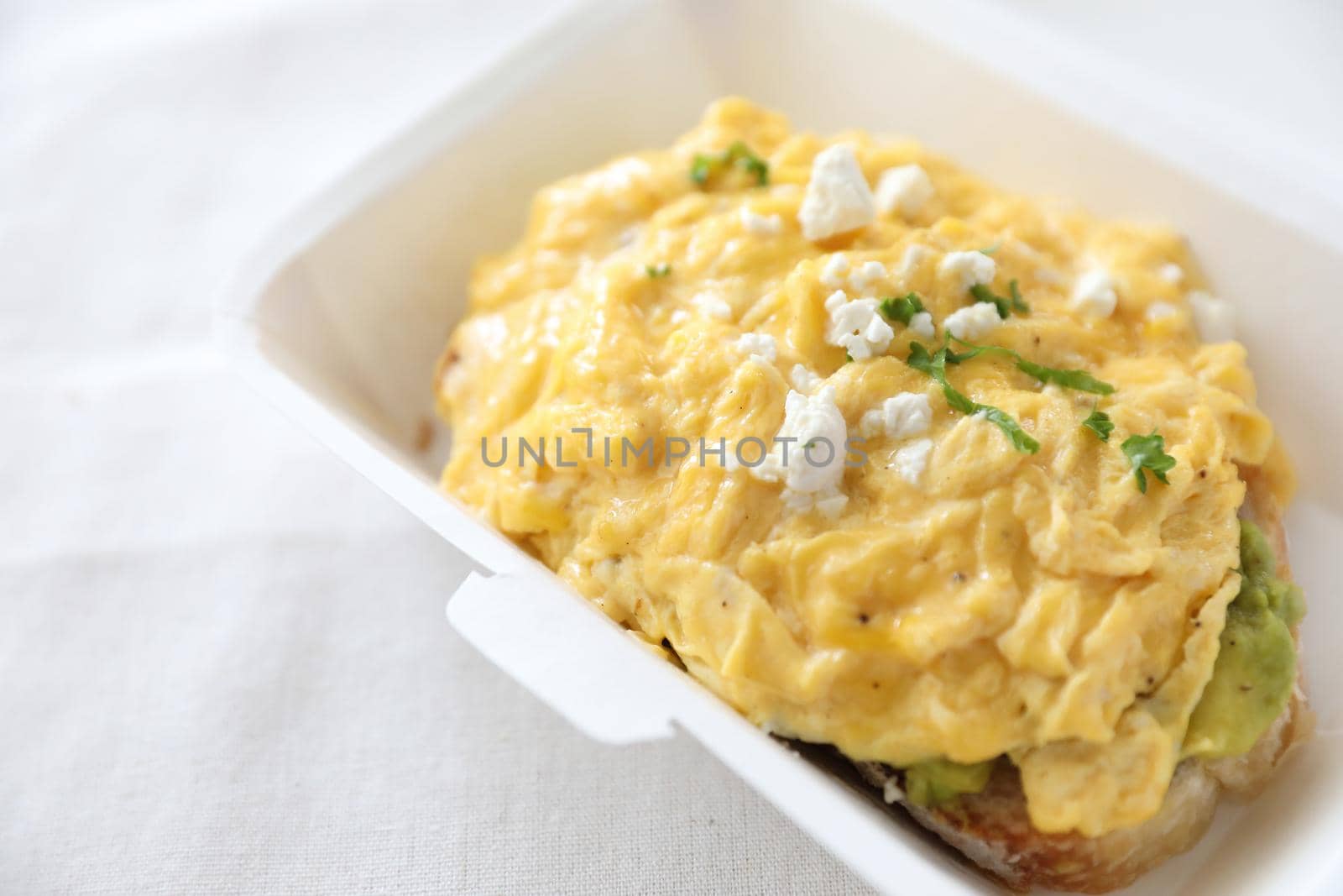 Avocado and scrambled eggs toast with delivery package in white background