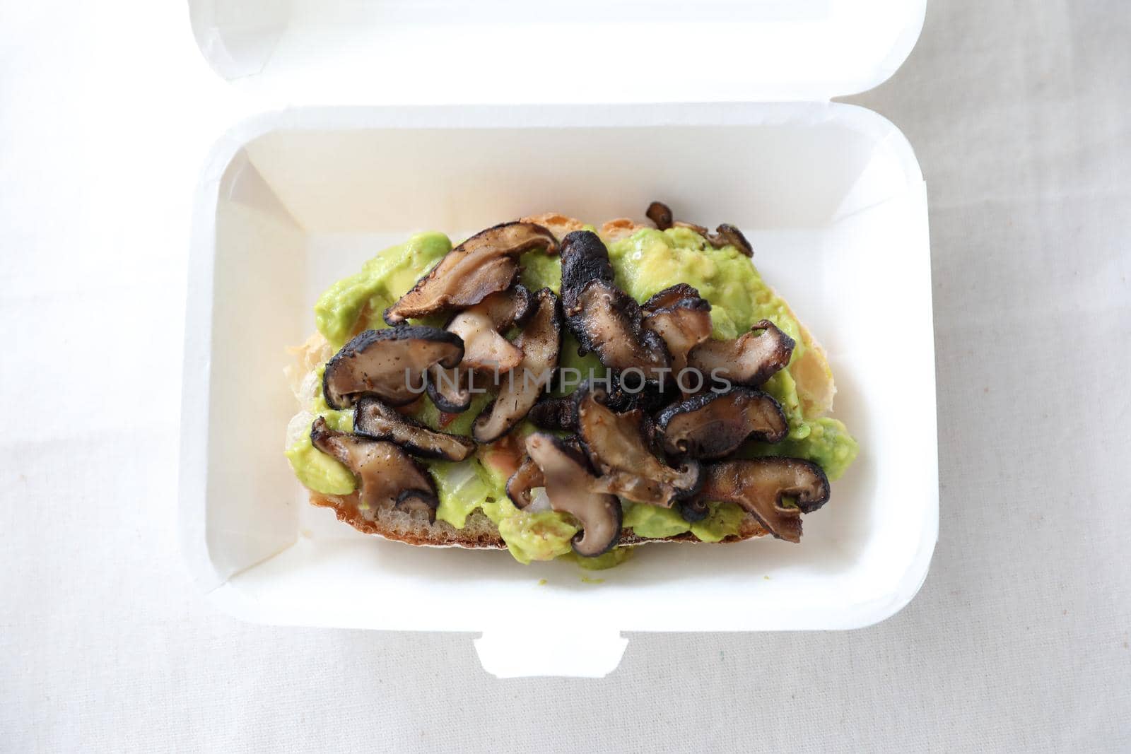 Toast with avocado and grilled mushroom with delivery package in white background by piyato