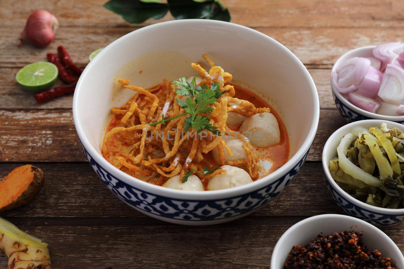 Local northern Thai food Egg noodle curry with meatballs on wood background by piyato