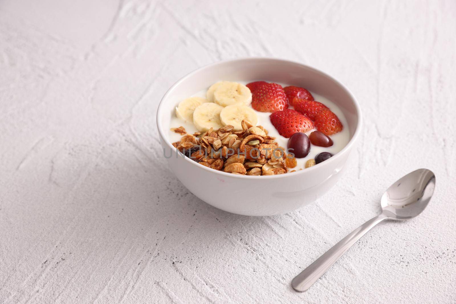 bowl of granola cereal with yogurt and berries isolated on white background