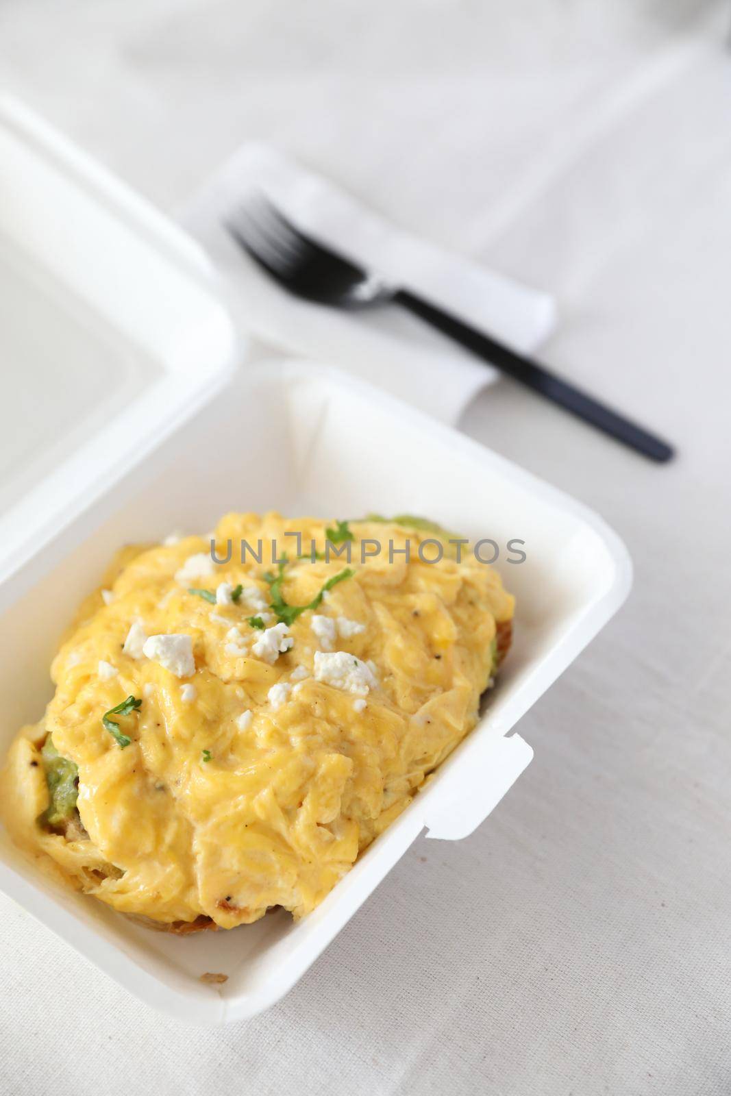 Avocado and scrambled eggs toast with delivery package in white background by piyato