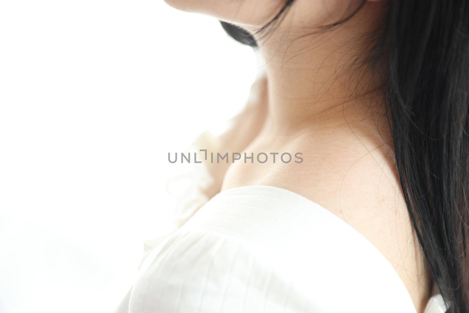 Close up of shoulder young Asian woman on bed relaxing in the morning light with white room by piyato