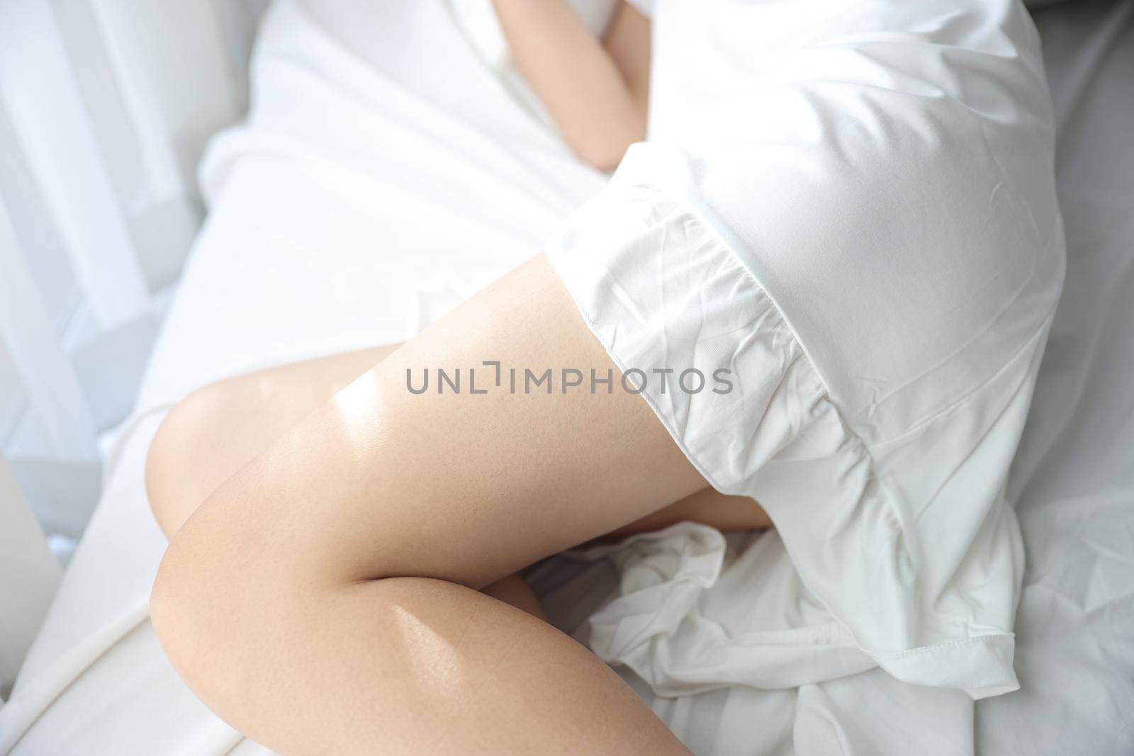 Beautiful young woman legs sleeping in the morning at white bedroom by piyato