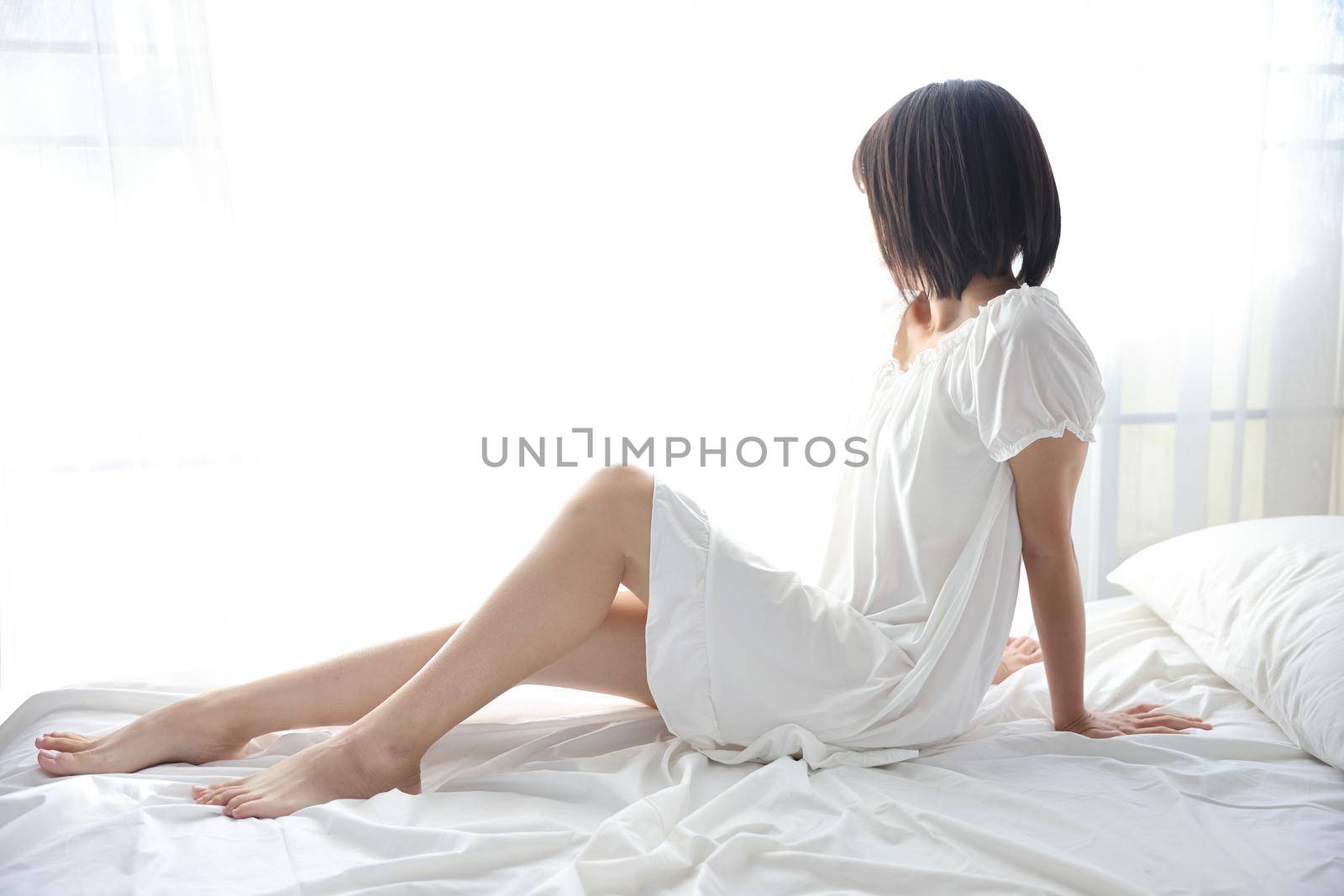 Beautiful young woman waking up in the morning at white bedroom