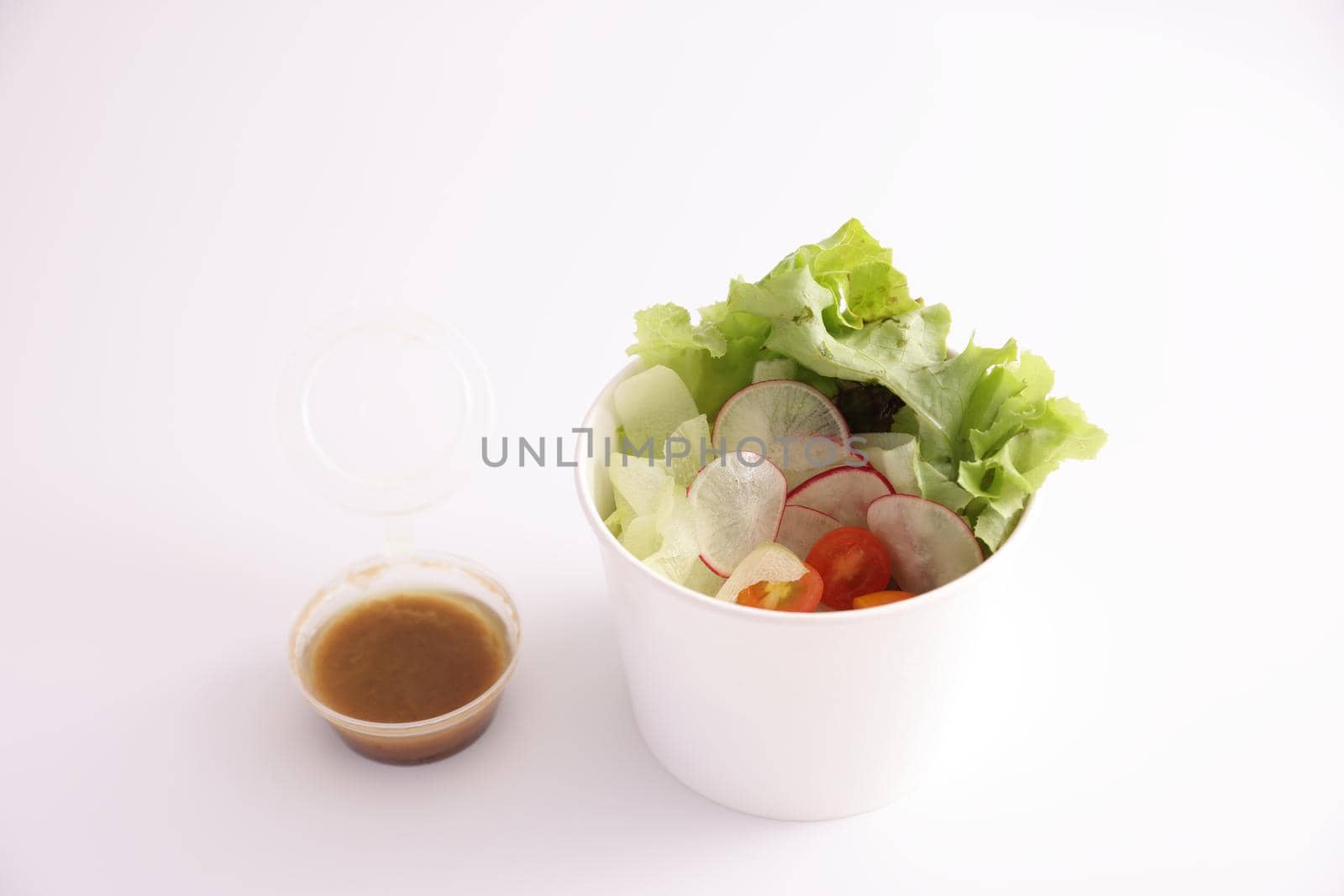 Salad in plastic package for take away or food delivery isolated on white background by piyato