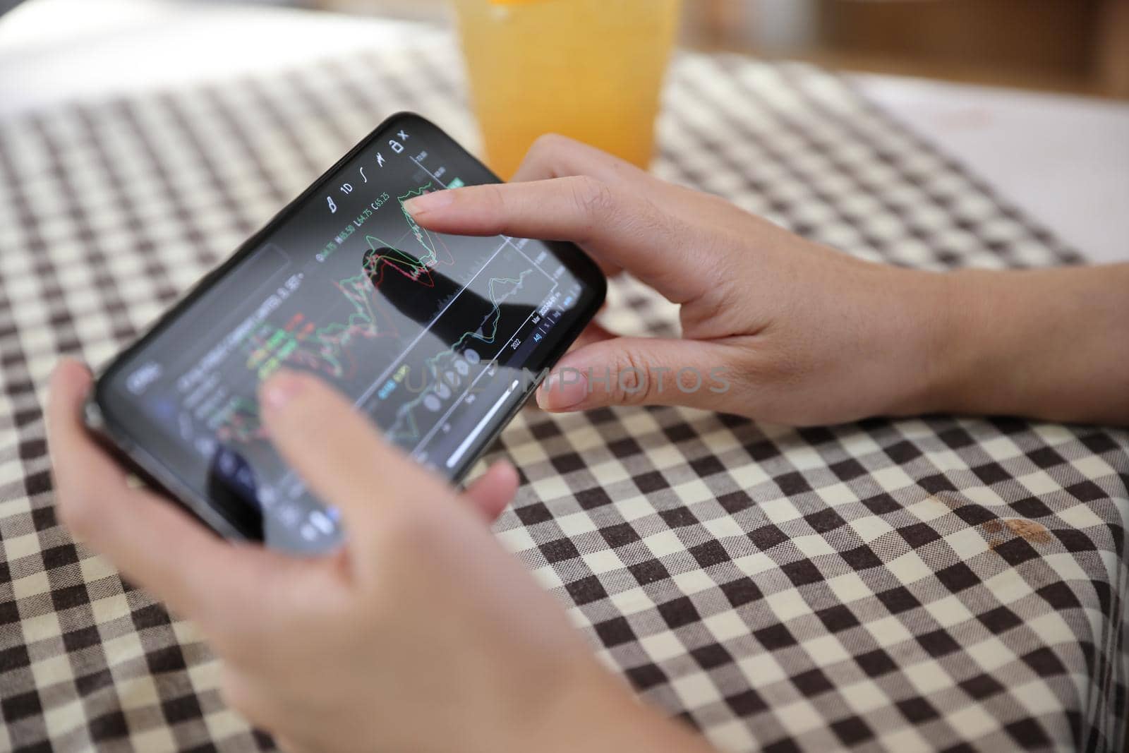 Woman hand using a smartphone for Stock exchange trading online in the coffee shop, business concept