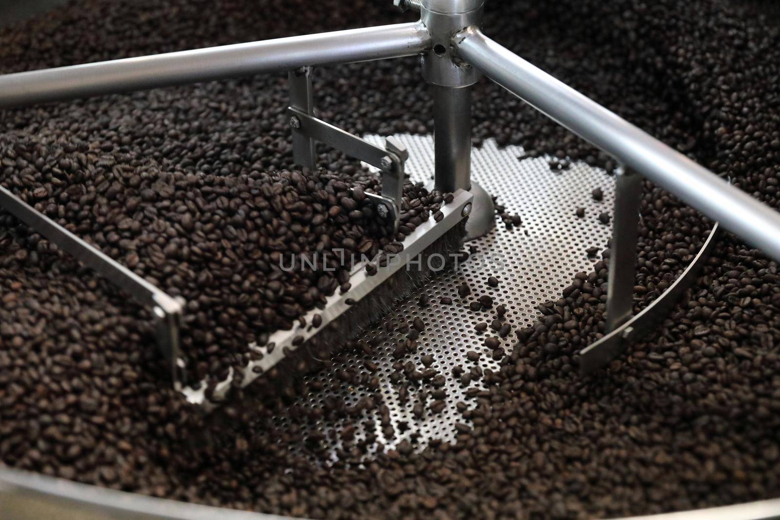 Coffee beans roasting with machine in close up by piyato