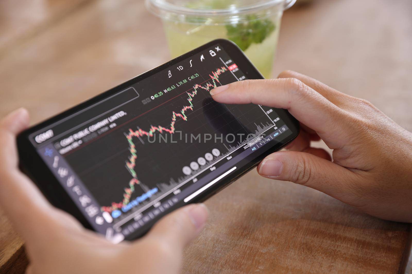 Woman hand using a smartphone for Stock exchange trading online in the coffee shop, business concept