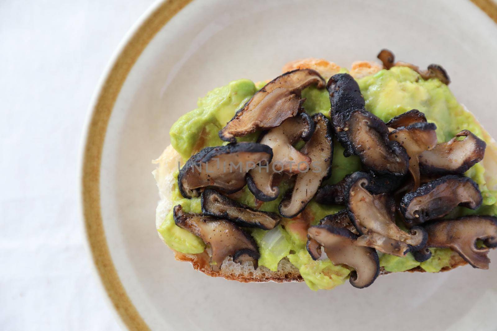 Toast with avocado and grilled mushroom in white background by piyato