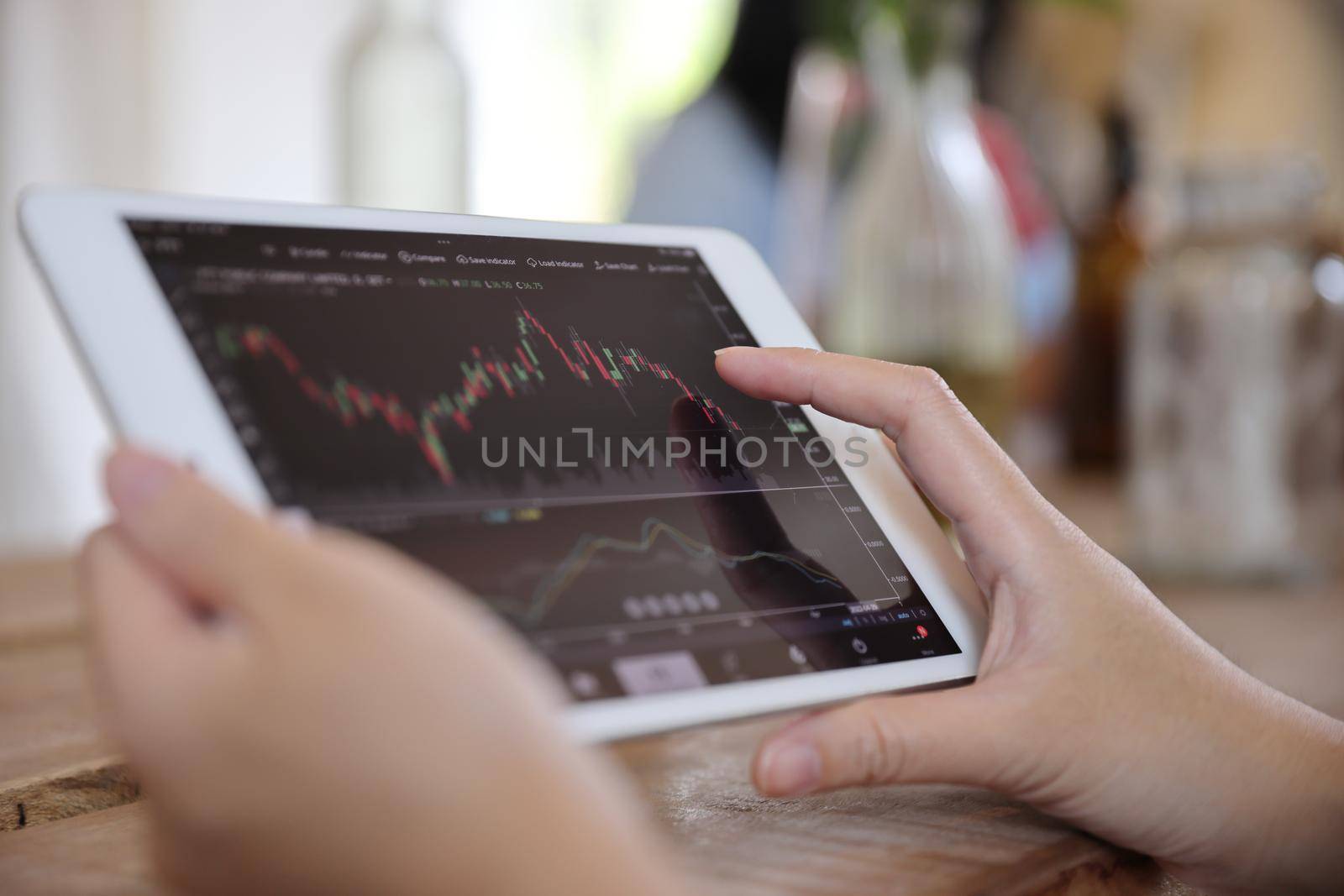 Woman hand using a tablet for Stock exchange trading online in the coffee shop, business concept
