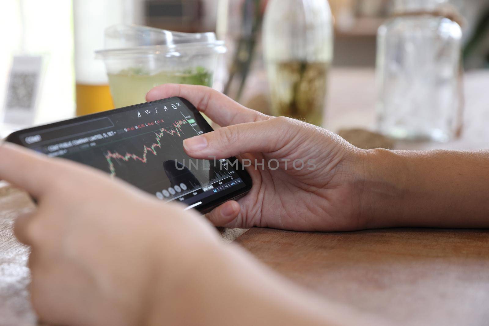 Woman hand using a smartphone for Stock exchange trading online in the coffee shop, business concept