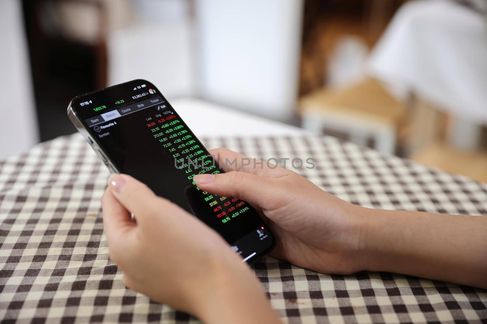 Woman hand using a smartphone for Stock exchange trading online in the coffee shop, business concept